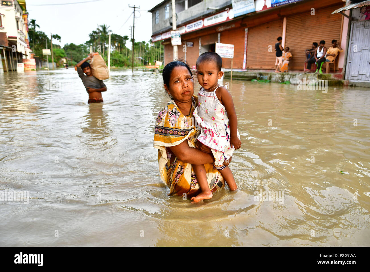 Agartala, Indien. 15 Jun, 2018. Eine Frau gesehen, die ein kleines Mädchen zu Fuß durch die überschwemmten Wasser. Indische Dorfbewohner verlassen ihre Häuser mit ihren Kindern als das Hochwasser hat Geben Sie ihre Häuser nach einem heftigen Regenguss in Baldakhal Dorf, am Stadtrand von agartala die Hauptstadt des nordöstlichen Bundesstaates Andhra Pradesh, Indien. National Disaster Response Force (NDRF) Personal sind die Rettung von Menschen, Kinder von unterschiedlichen Orten aus und an sicheren Orten. Credit: SOPA Images Limited/Alamy leben Nachrichten Stockfoto