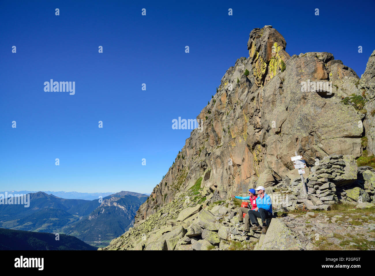 Zwei Wanderer sitzen unter einem Rock spire und Blick auf die Berge, Trans-Lagorai, Lagorai, Dolomiten, UNESCO-Heri Stockfoto