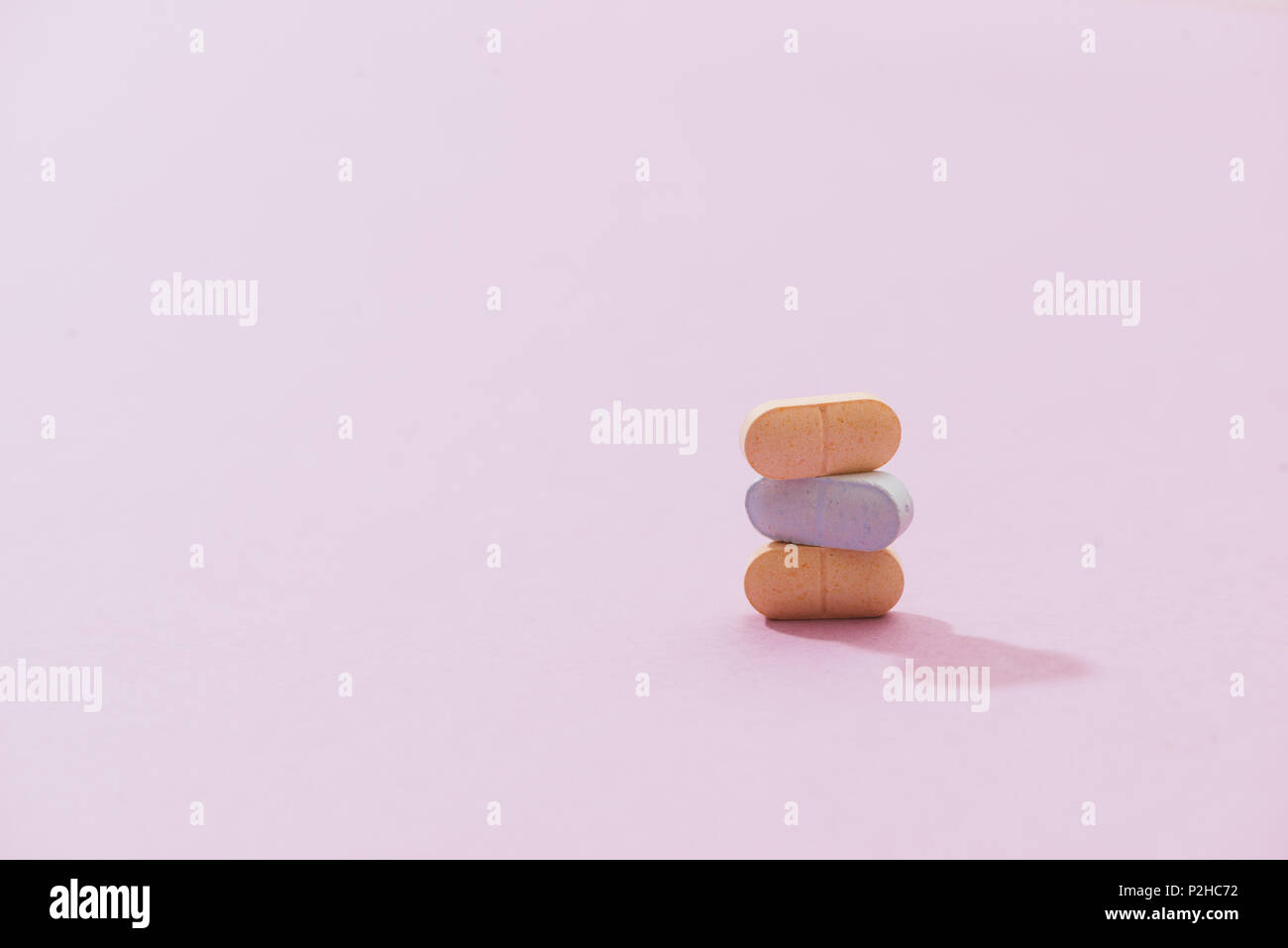 Stapel von Pille und Kapsel mit Schatten auf rosa Hintergrund Stockfoto