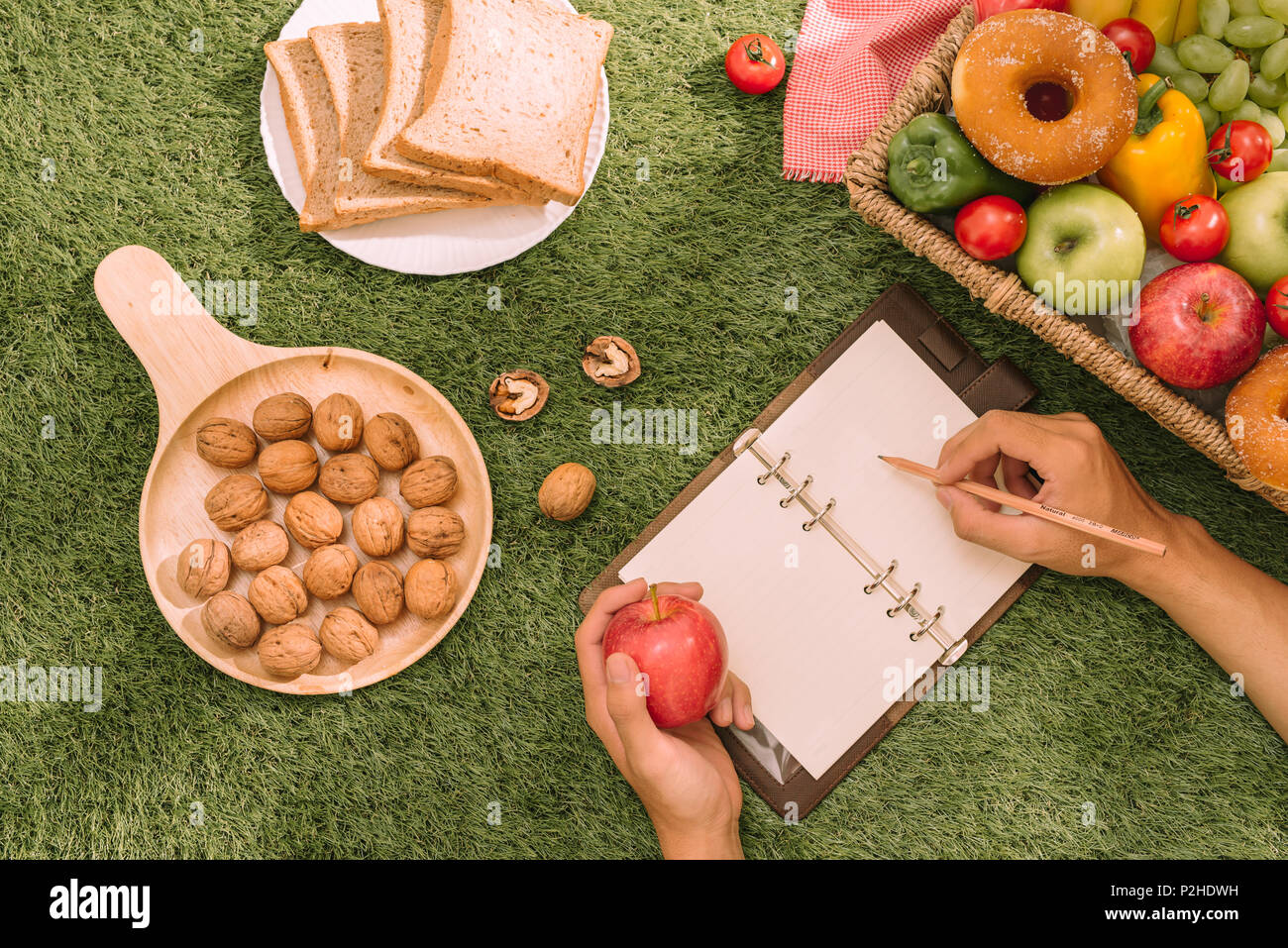 Picknick Weidenkorb mit Essen, Brot, Obst und Orangensaft auf einer rot-weiß karierten Tuch in das Feld mit der grünen Natur Hintergrund. Picknick conce Stockfoto