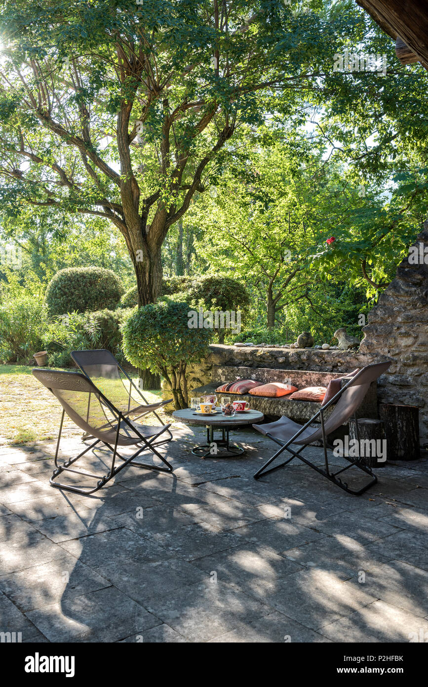 Liegestühlen und Tisch im Schatten des Baumes, Luberon. Stockfoto