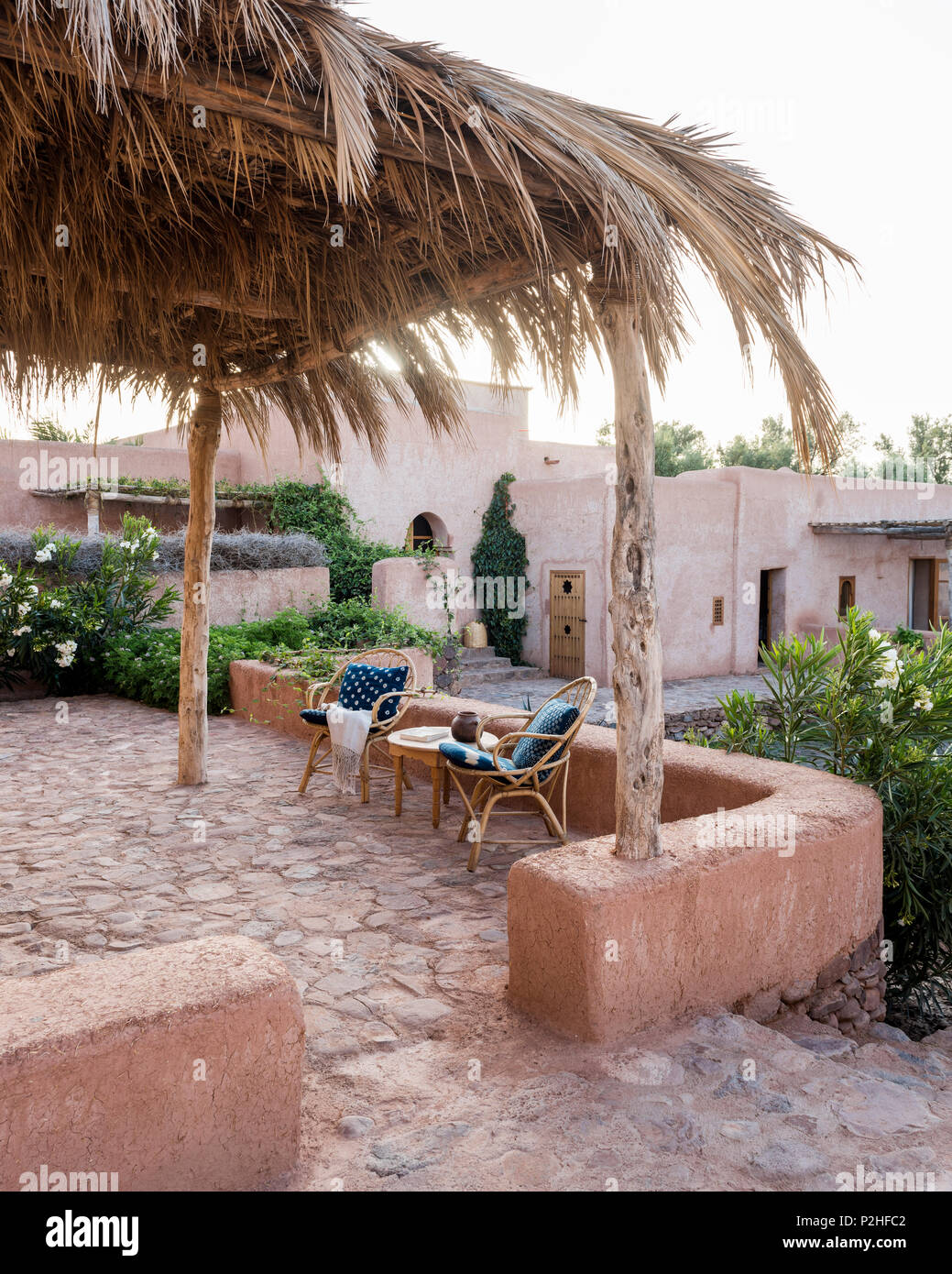 Ein paar Rattan Stühle auf der Terrasse im Garten mit Erde Mauern, Kräuter und marokkanische Wildpflanzen. Garten Design von Arnaud Casaus Stockfoto