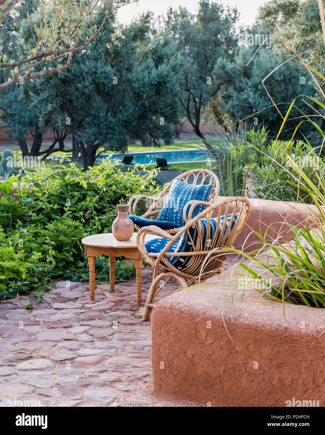 Ein paar Rattan Stühle im Garten mit Erde Mauern, Kräuter und marokkanische Wildpflanzen. Garten Design von Arnaud Casaus Stockfoto