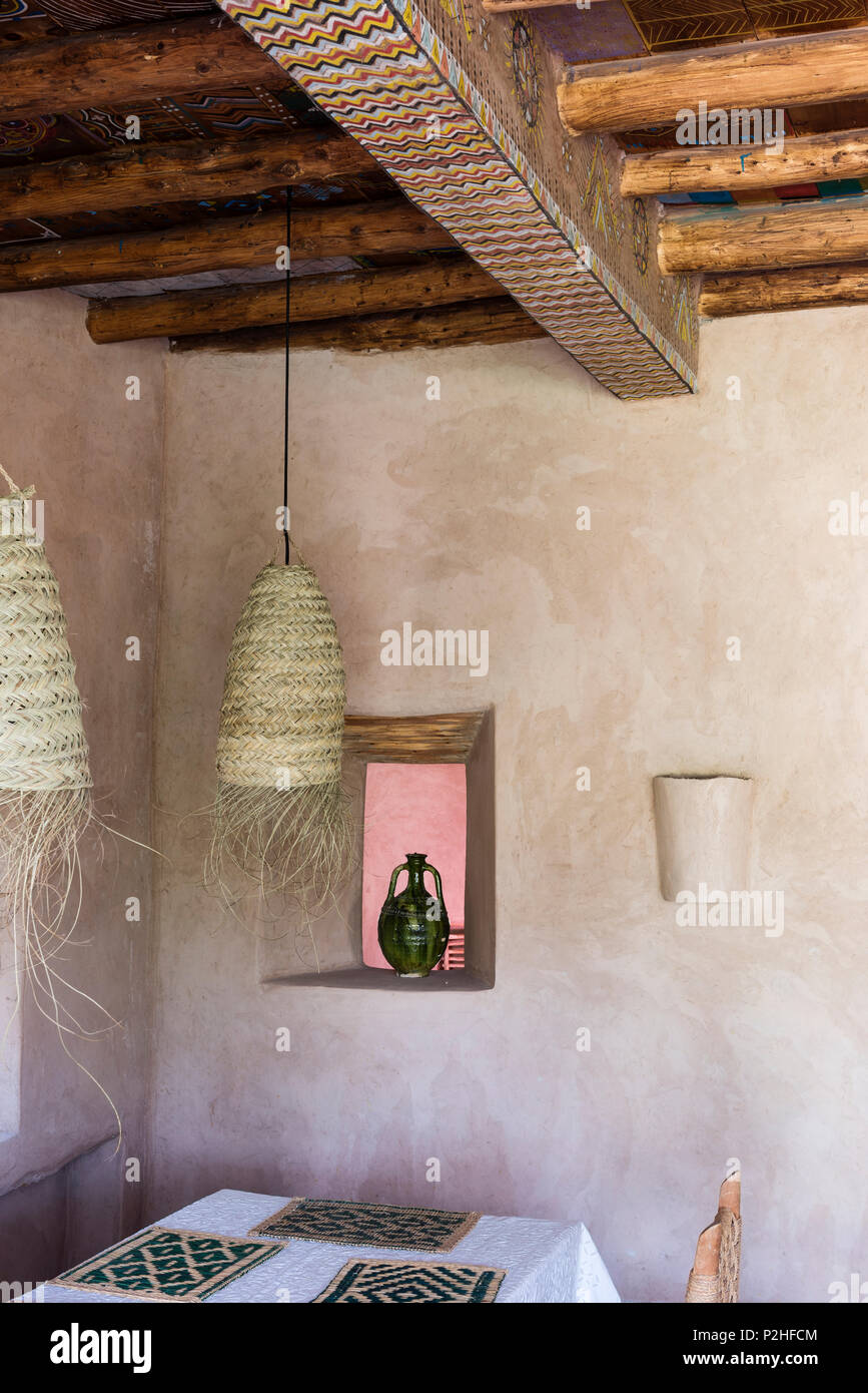 Rattan Pendelleuchten oberhalb Esstisch in Berber Stil Zimmer mit Holzbalkendecke und Erde Mauern Stockfoto