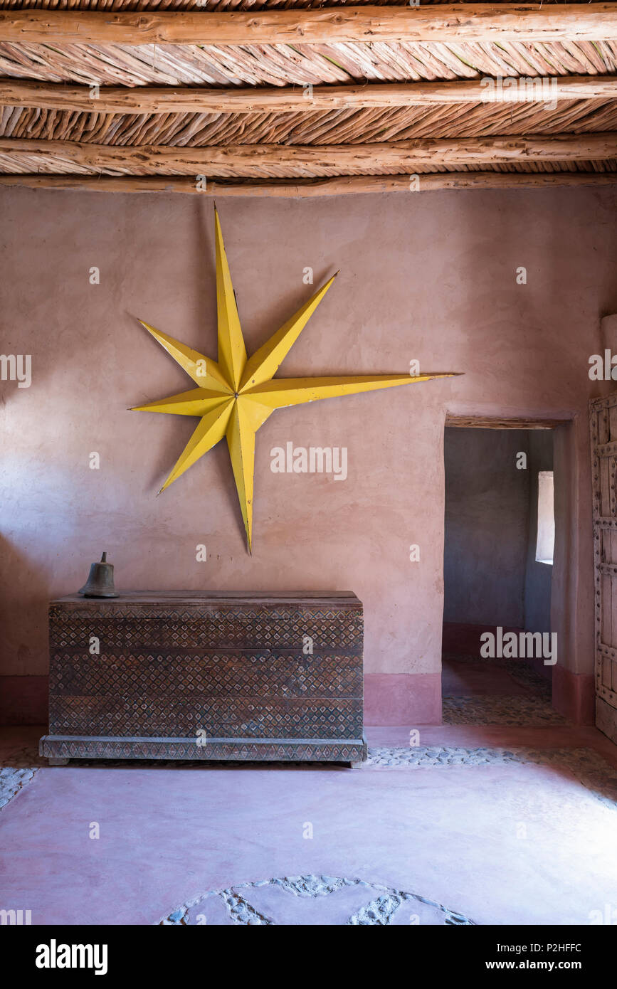 Große gelbe Sterne auf der Erde an der Wand im Eingangsbereich der Berber Lodge mit antiken Holzmöbeln Brust hing und verzierte getäfelte Tür Stockfoto