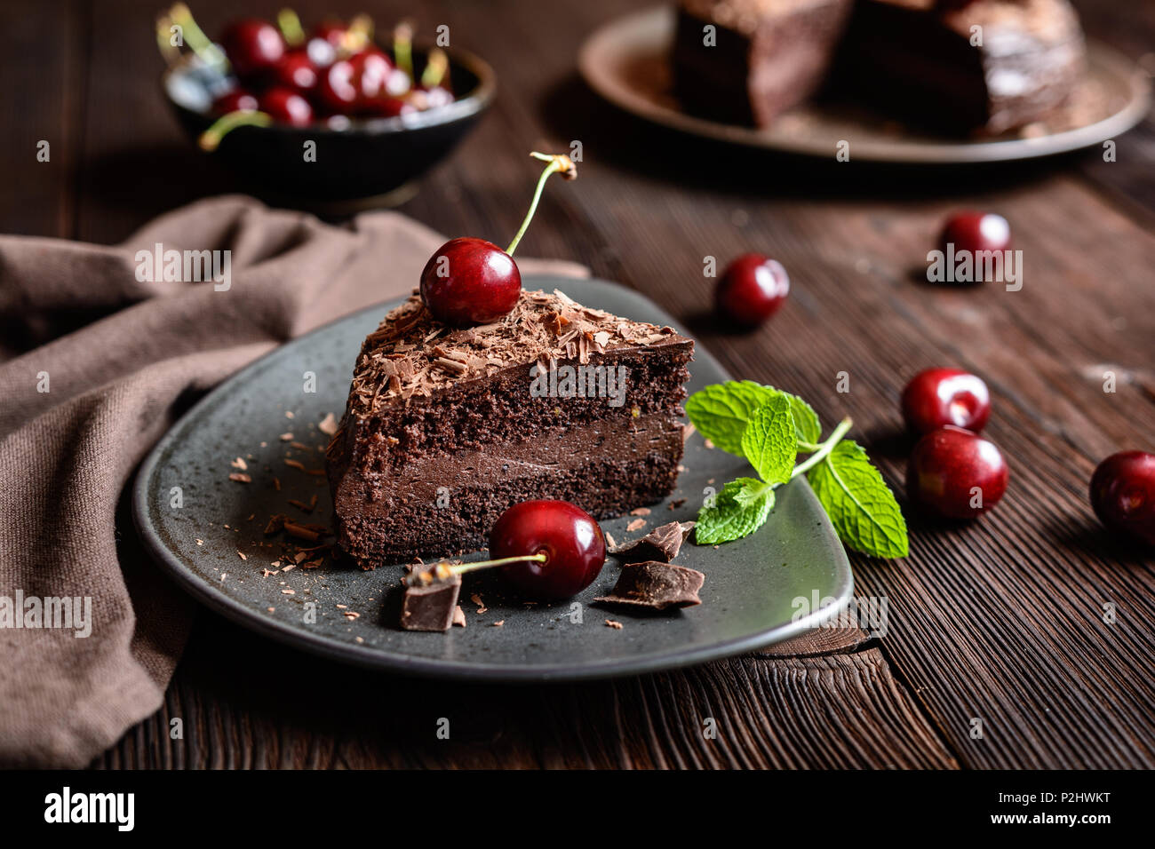 Schokoladenkuchen mit Kakao Schlagsahne gefüllt und mit Schokolade Spänen und Cherry dekoriert Stockfoto