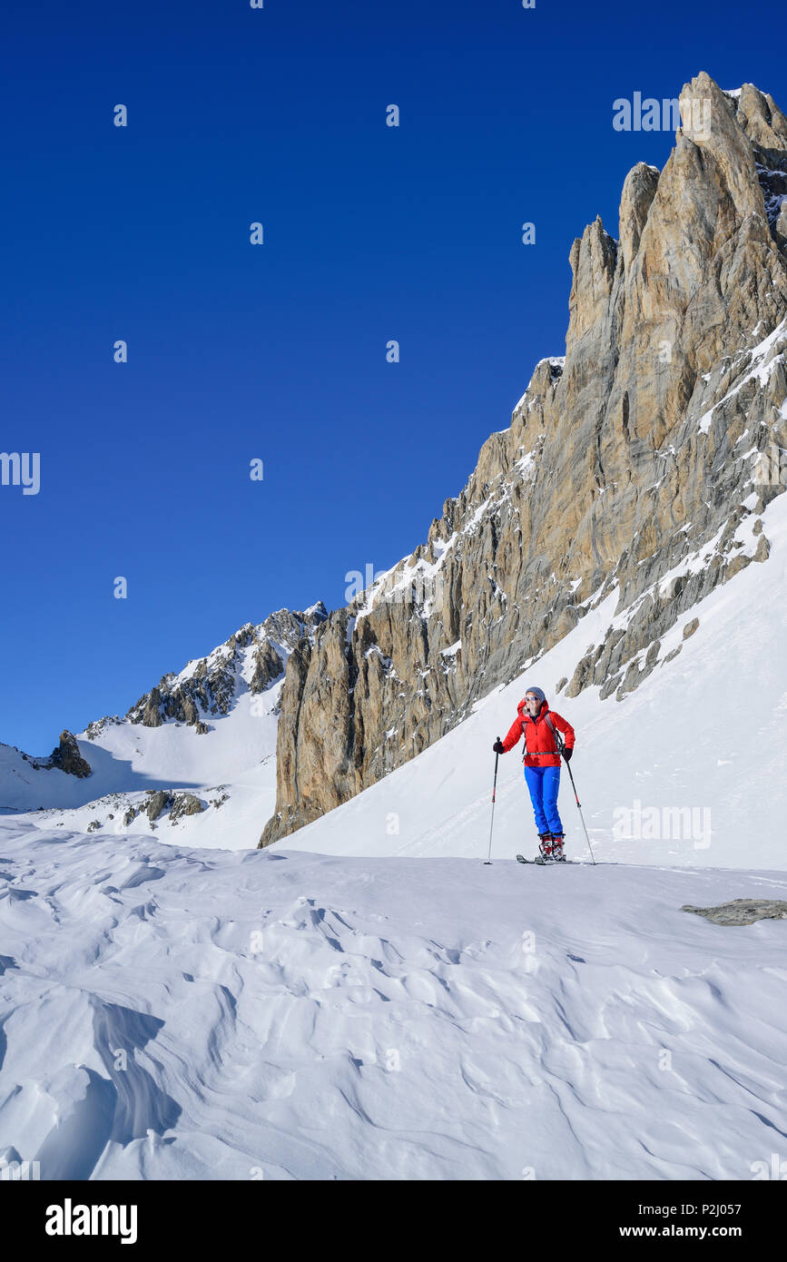 Frau zurück Langlaufen unter der Felswand des Monte Sautron, Valle Maira, Cottischen Alpen, Piemont, Italien stehend Stockfoto