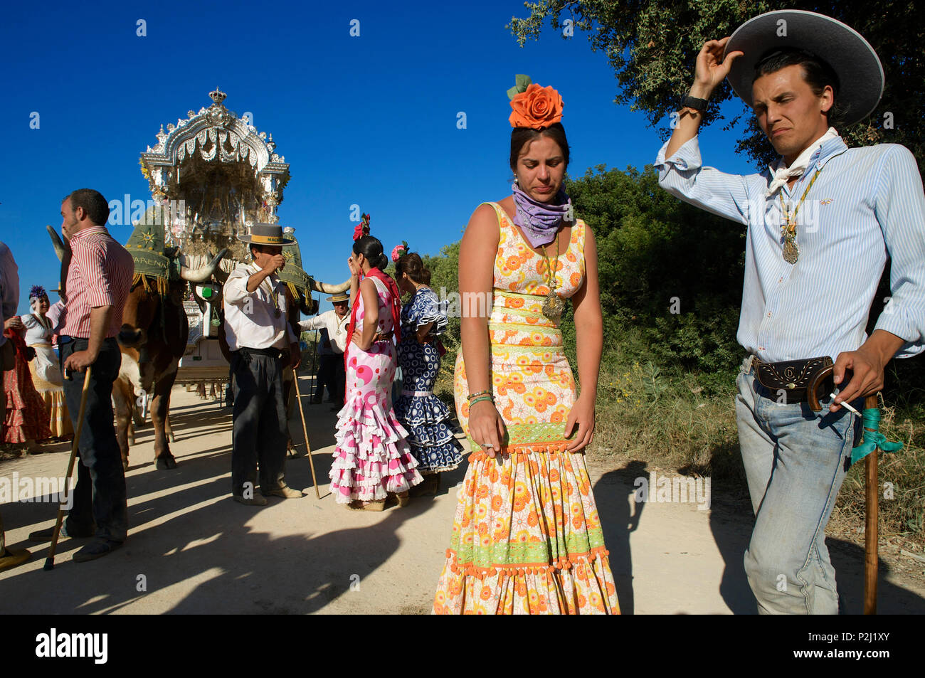 Pilger mit Ochsenkarren und Frauen tragen Flamenco Kleider auf einer Pilgerreise "Nuestra Señora de El Rocio" auf der Strecke La Raya Real Stockfoto