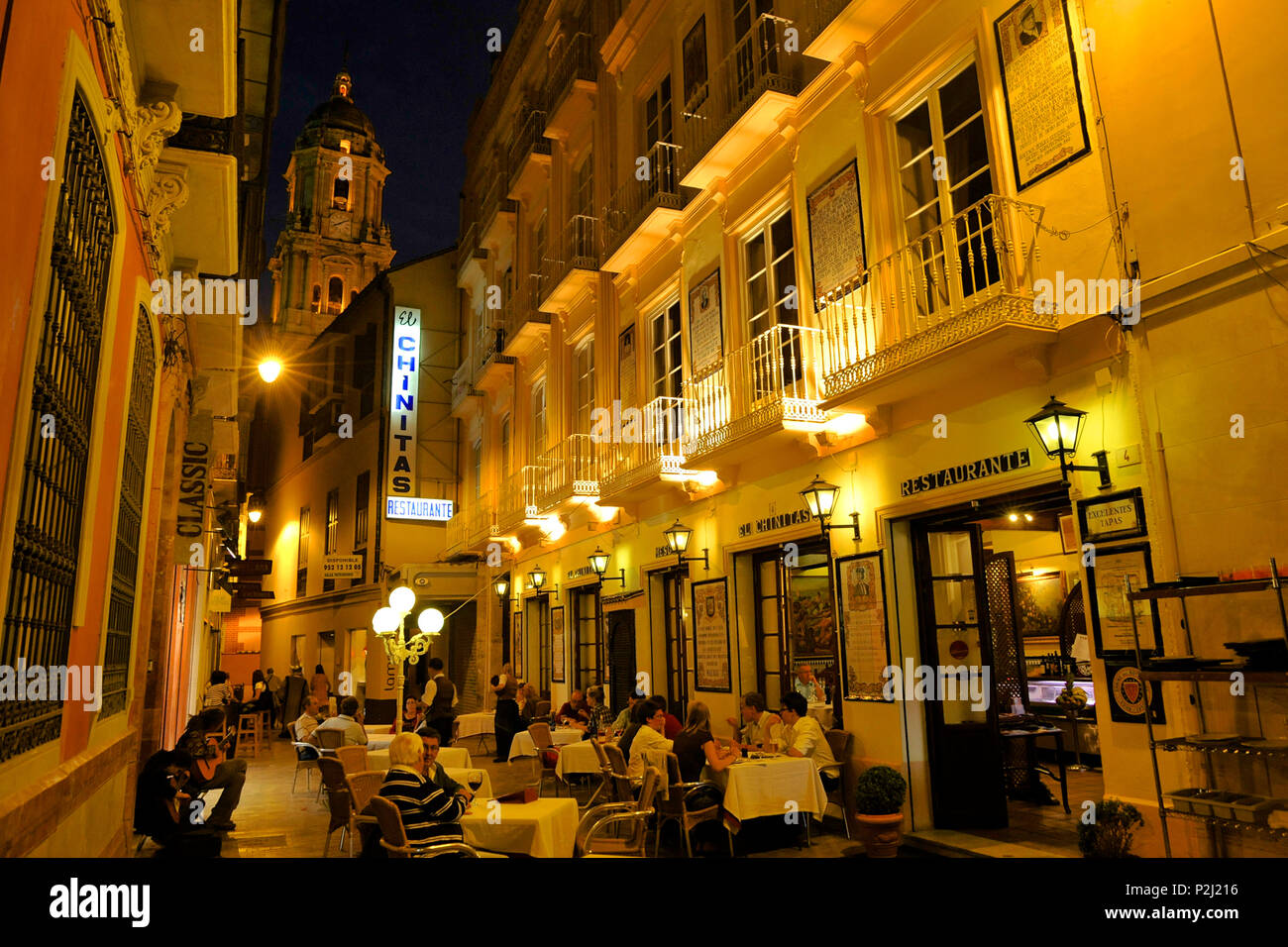Kleine Gasse mit Restaurants und Tischen und Blick auf den Turm der Kathedrale von Málaga im Abendlicht, Malaga, Andalusien, Stockfoto