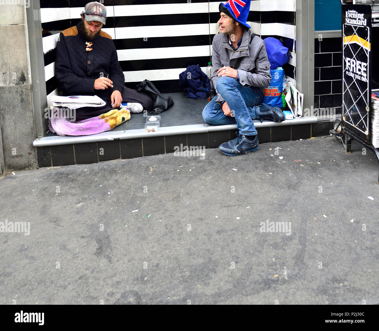 Zwei obdachlose Männer in einem Türrahmen sitzend, The Strand, London, England, UK. Stockfoto