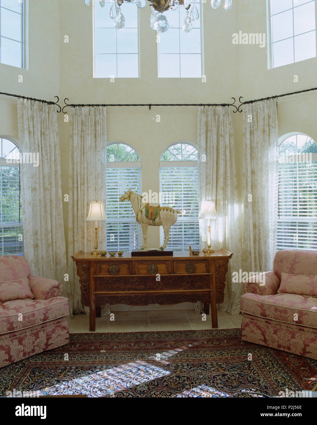 Rosa Stühle an beiden Seiten der Tabelle vor der Fenster mit voile Gardinen in doppelter Höhe Wohnzimmer Stockfoto