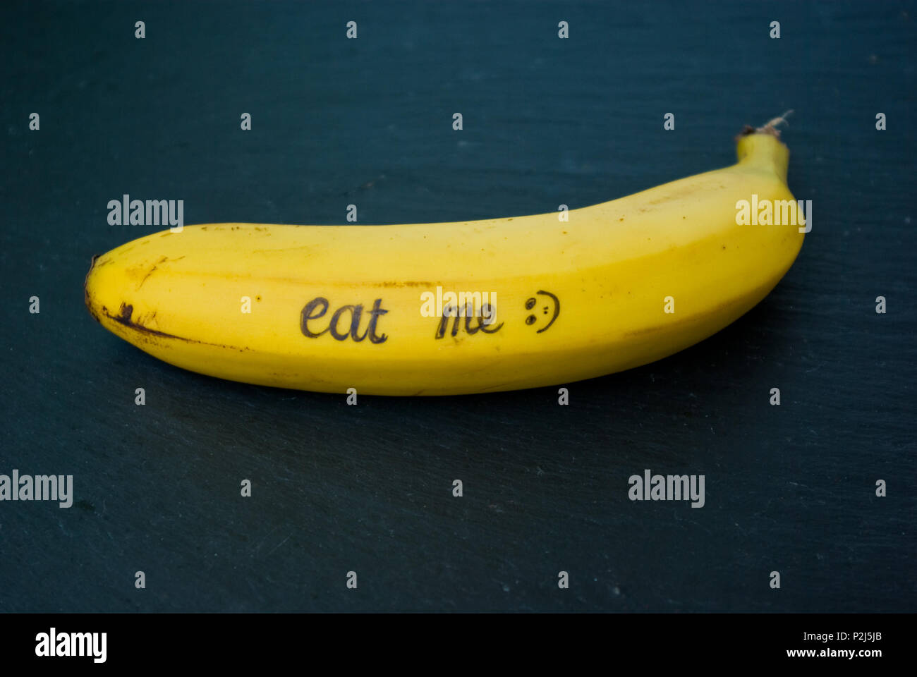 Reife gelbe Banane auf einen schwarzen Stein Tabelle mit Schreiben ' mich essen' Stockfoto