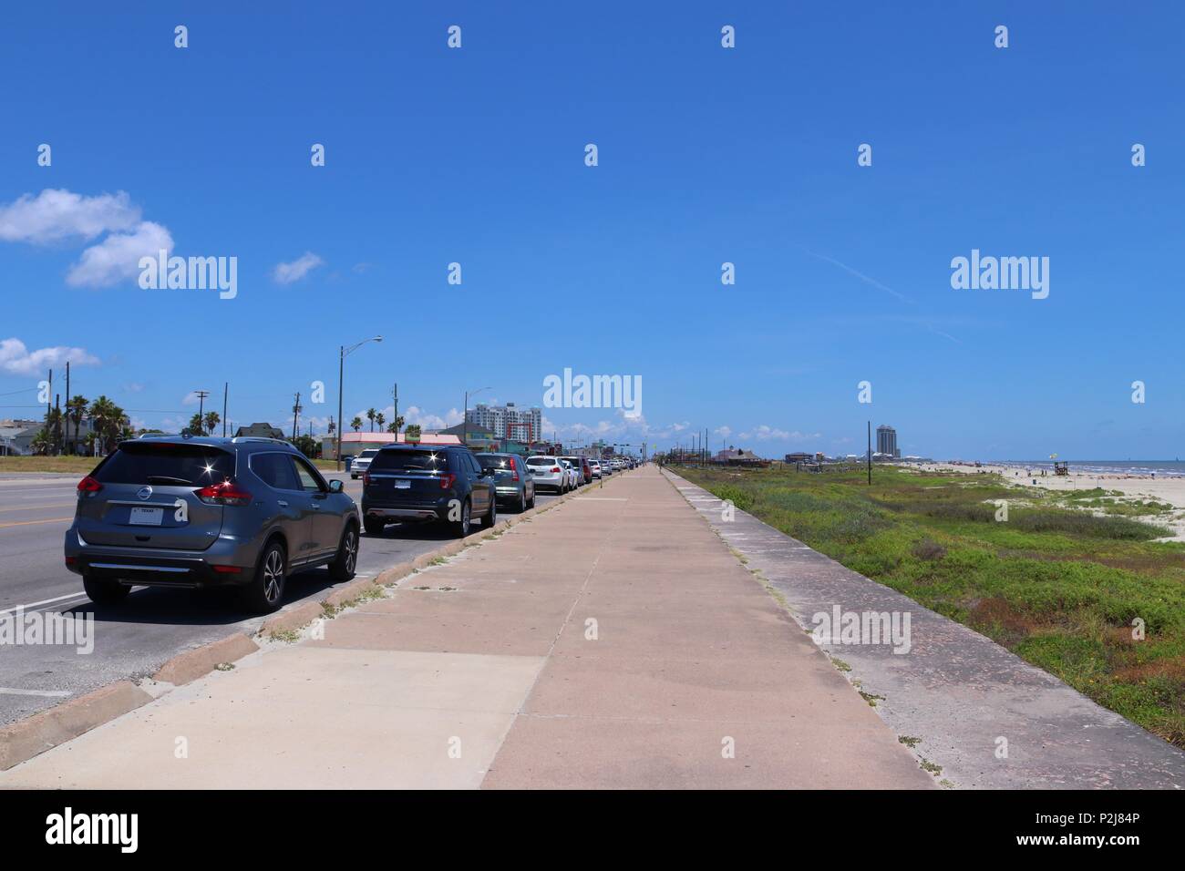 Urban Street Szene in Texas in den Vereinigten Staaten von Amerika. Boulevard in Galveston, Lone Star State. Perspektivische Ansicht der geparkten Autos, Gehweg und Strand. Stockfoto