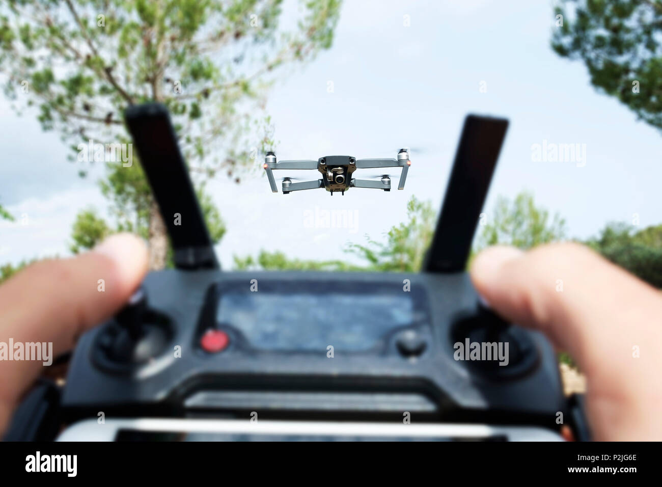 Nahaufnahme von einem kaukasischen Mann Betrieb einer Drohne, aus der Ferne mit einem Smartphone gesteuert, in einer natürlichen Landschaft Stockfoto