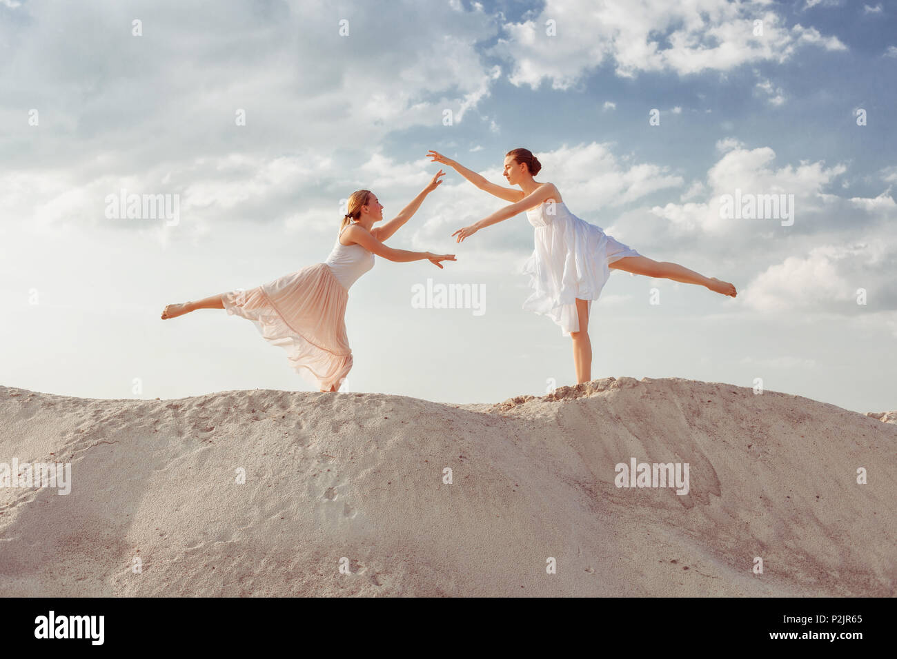 Zwei junge Tänzer tanzen in der Wüste im Sand. Stockfoto