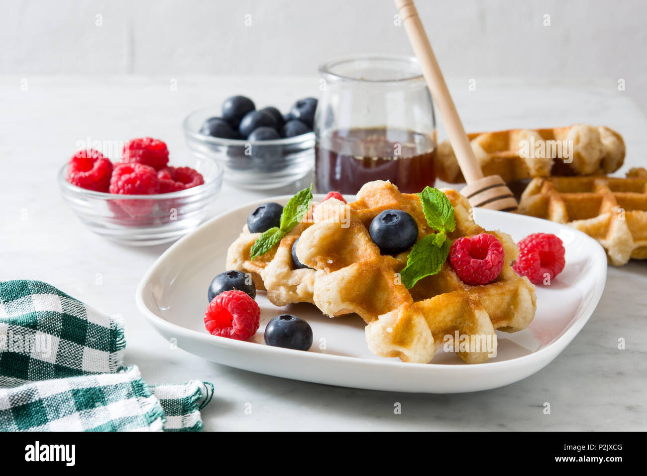 Traditionelle belgische Waffeln mit Heidelbeeren und Himbeeren auf weißem Marmor Stockfoto
