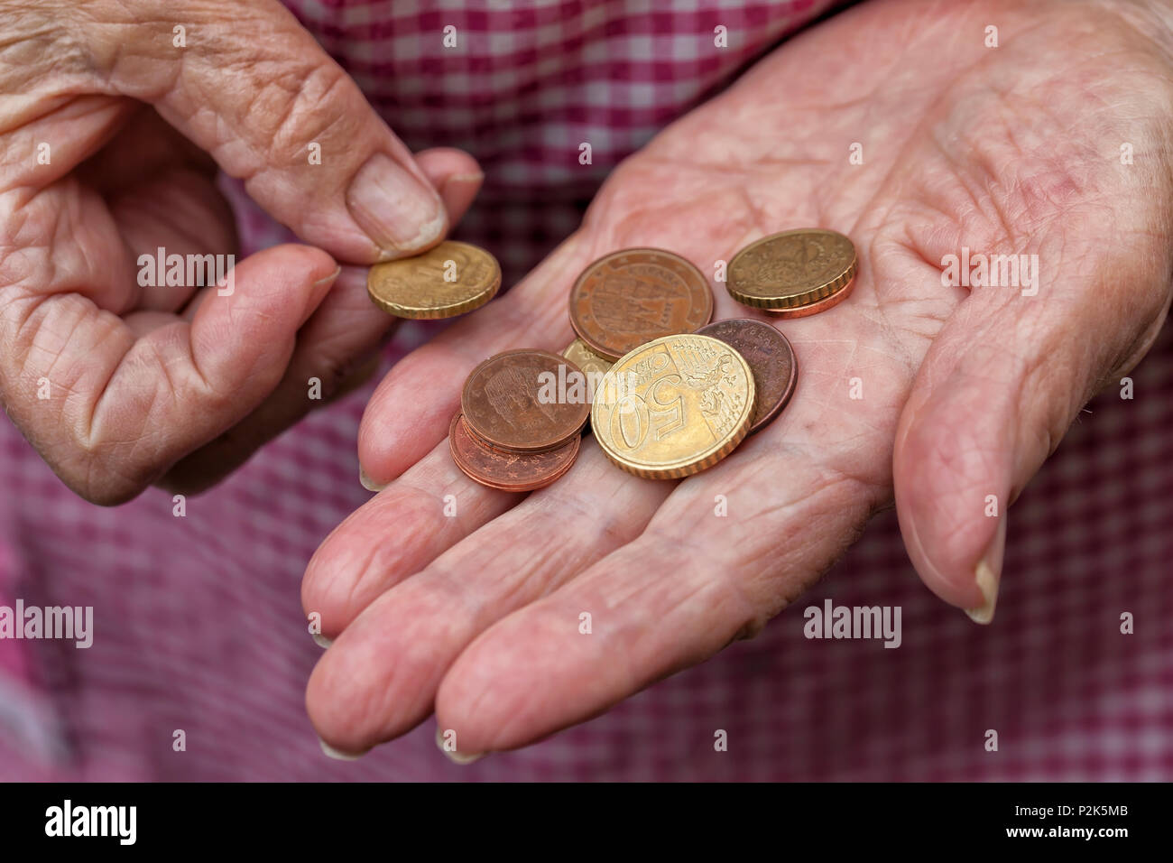 Eine ältere Dame hält ein paar Cent von Euro in den Händen. Stockfoto