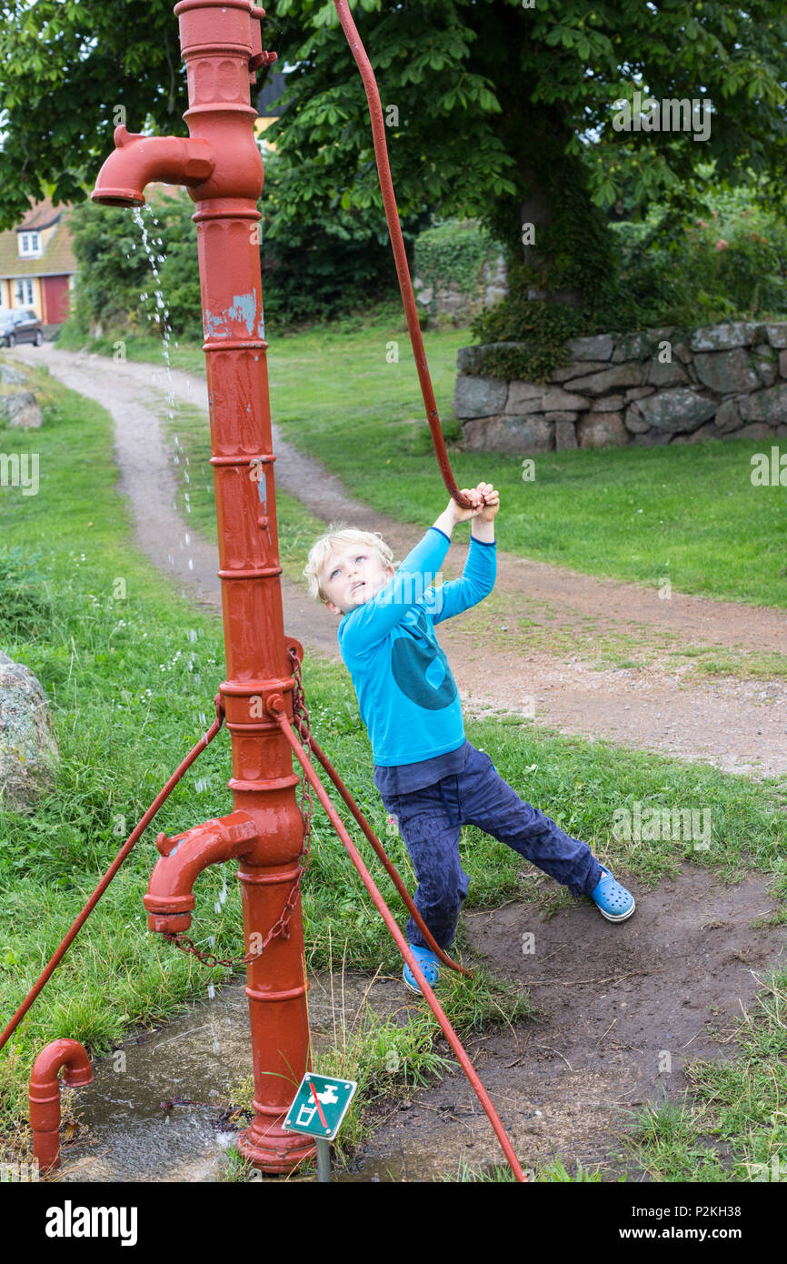 5 Jahre alter Junge Pumpen von Wasser mit einem traditionellen Wasserpumpe, Ostsee, HERR, Bornholm, Blokhus, Dänemark, Europa Stockfoto