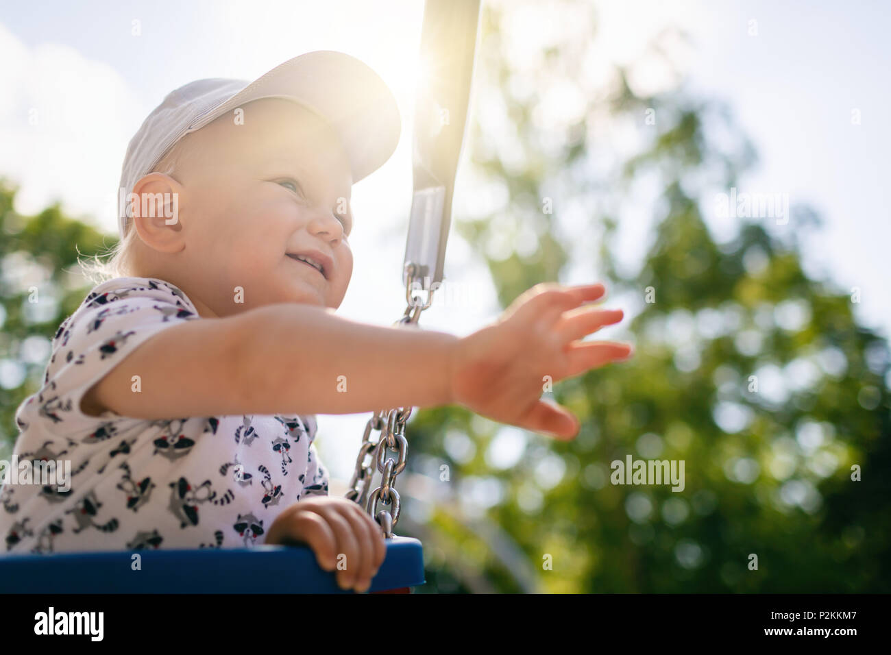 Baby Boy spielen in den Spielplatz. Portrait von lächelnd Kleinkind weg schauen mit glücklichen Gesicht, Spaß zu haben. Schlingern auf sonnigen Sommertag im Freien. Stockfoto