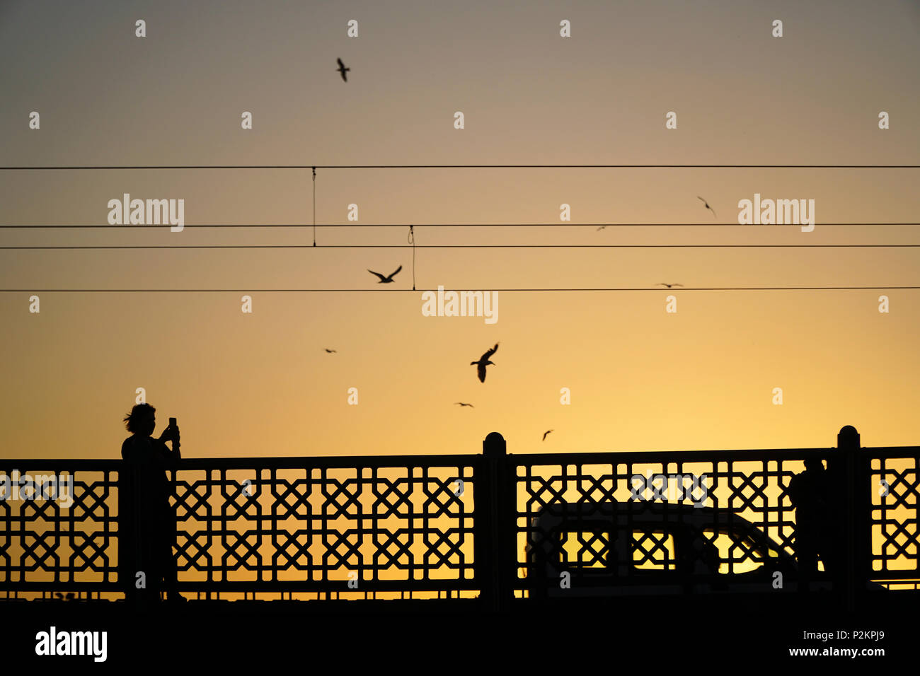 Istanbul, Türkei - 12. Juni 2018: die Silhouetten der einige Leute mit einem Auto auf der Galata Brücke in Istanbul. Eine Frau nimmt mobile Photo. Stockfoto