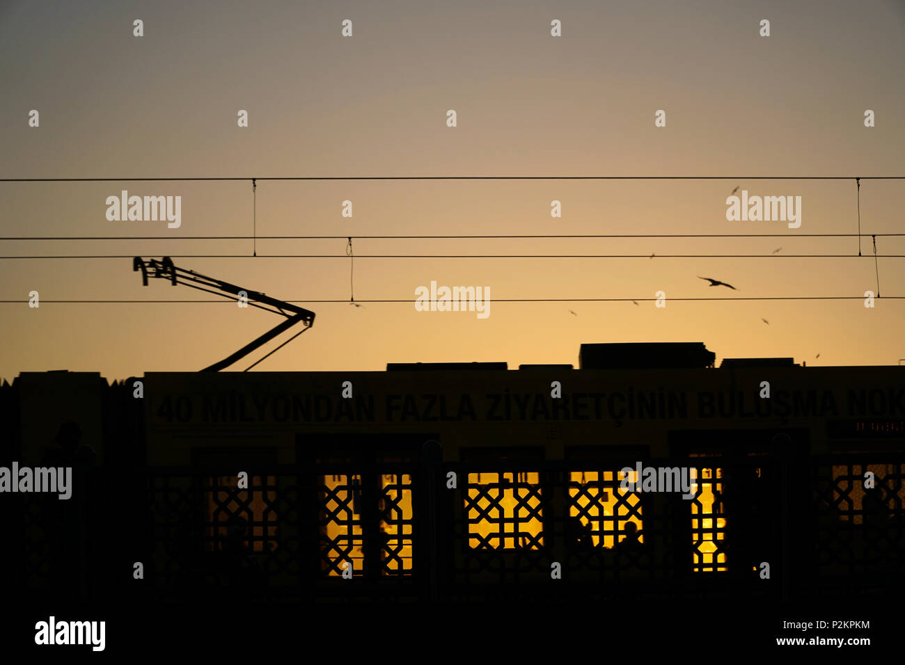 Istanbul, Türkei - 12. Juni 2018: Silhouetten auf der Galata Brücke in Istanbul. Die Straßenbahn ist vorbei. Einige Leute sind in der Straßenbahn sichtbar. Stockfoto