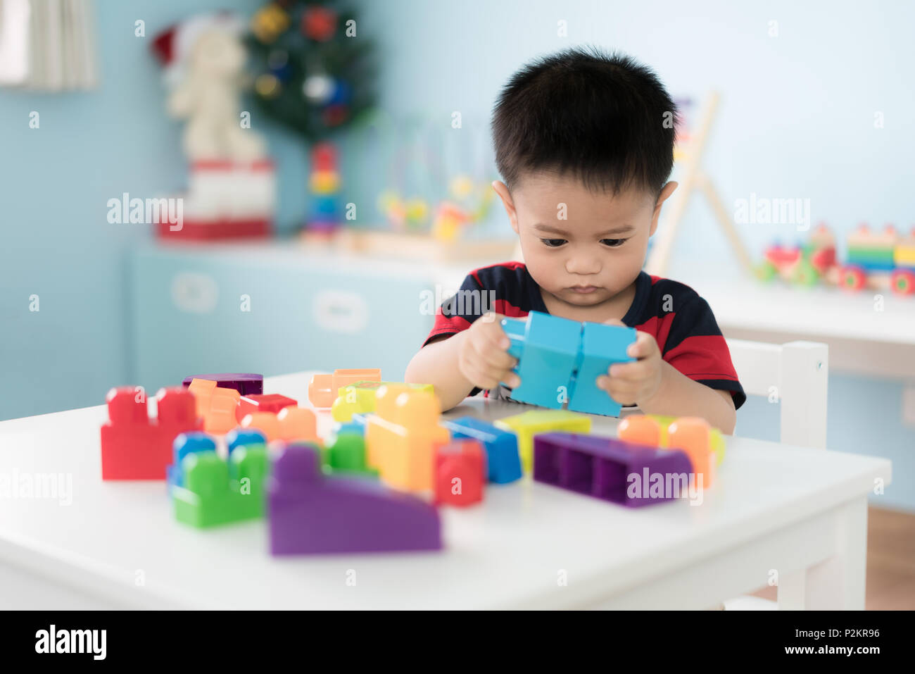 Adorable asiatischen Kleinkind Baby Junge sitzt auf einem Stuhl und Spielen mit Farbe block Spielzeug zu Hause. Stockfoto