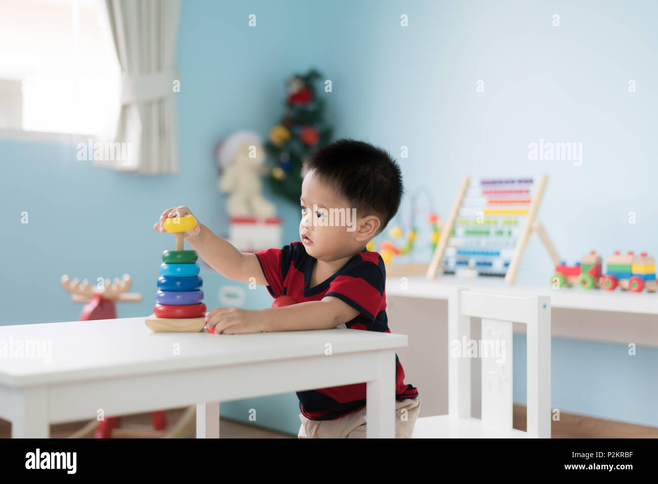 Adorable asiatischen Kleinkind Baby Junge sitzt auf einem Stuhl und Spielen mit Farbe entwicklungspolitischen Spielzeug zu Hause. Stockfoto