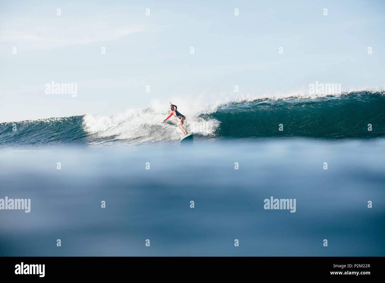 Junge Frau im Neoprenanzug Surfen auf den Wellen Stockfoto