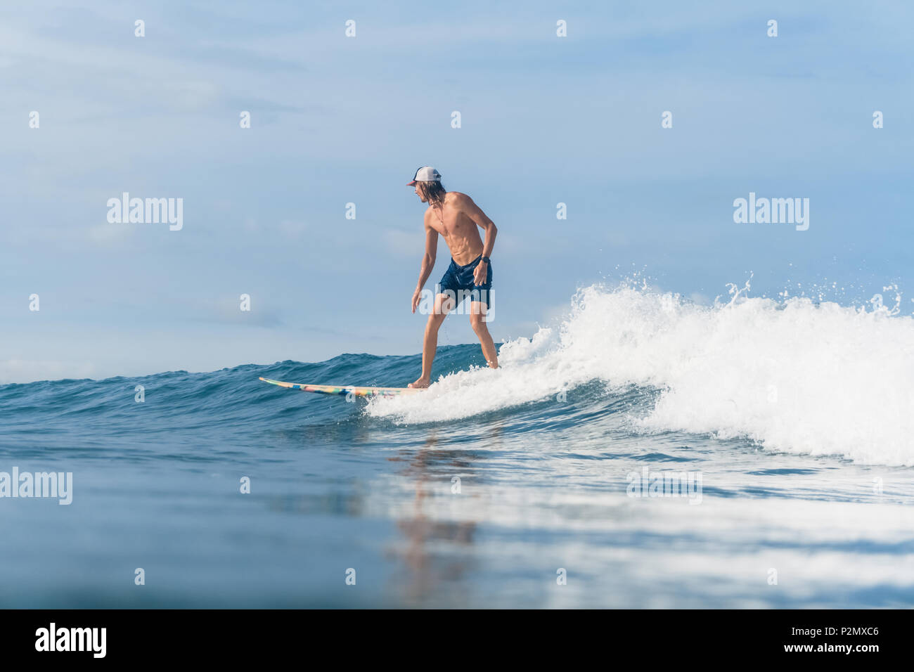 Seitenansicht des Menschen in Badeshorts Surfen im Ozean Stockfoto