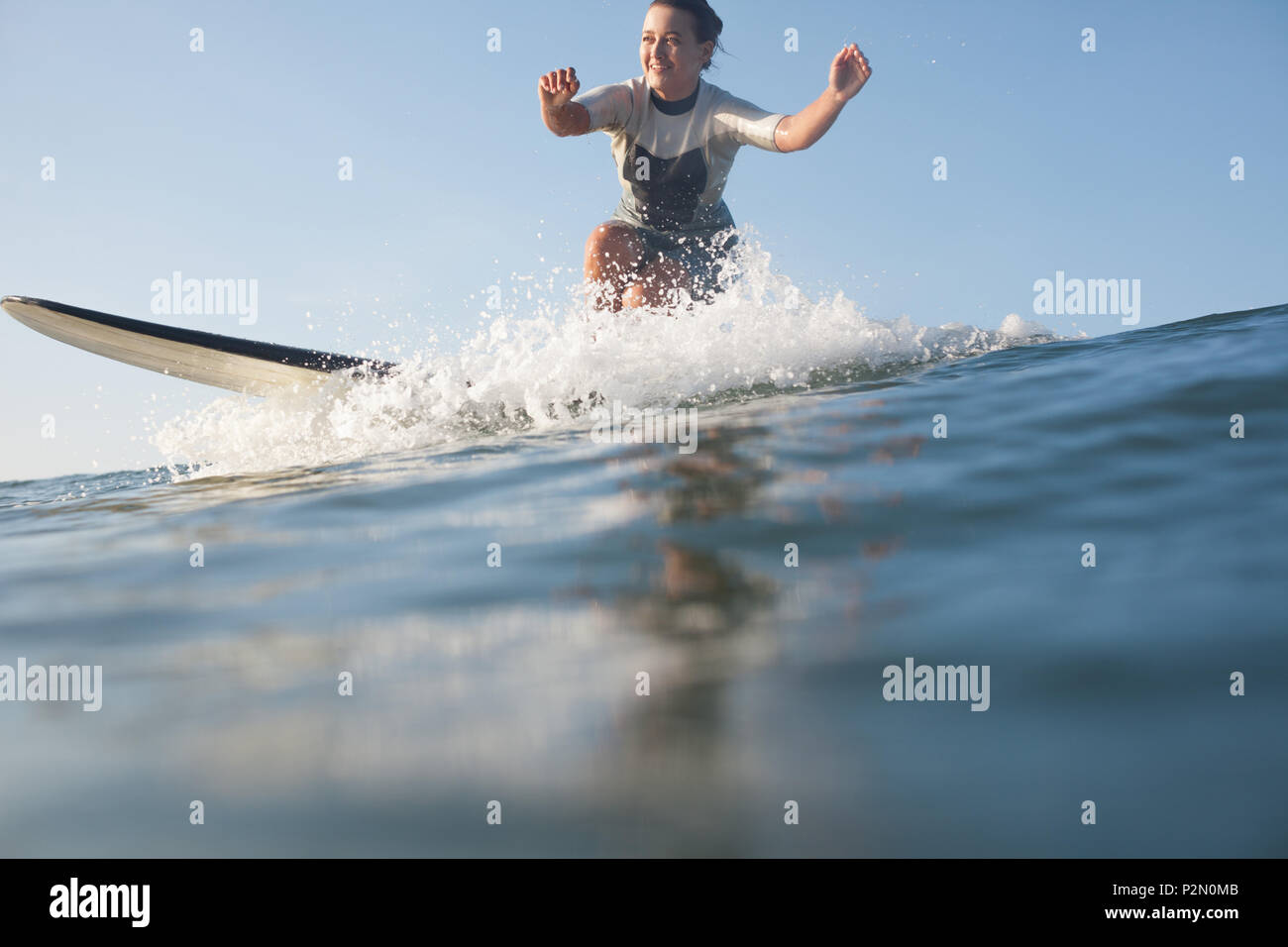 Lächelnd Sportlerin surft" auf der Welle im Ozean Stockfoto