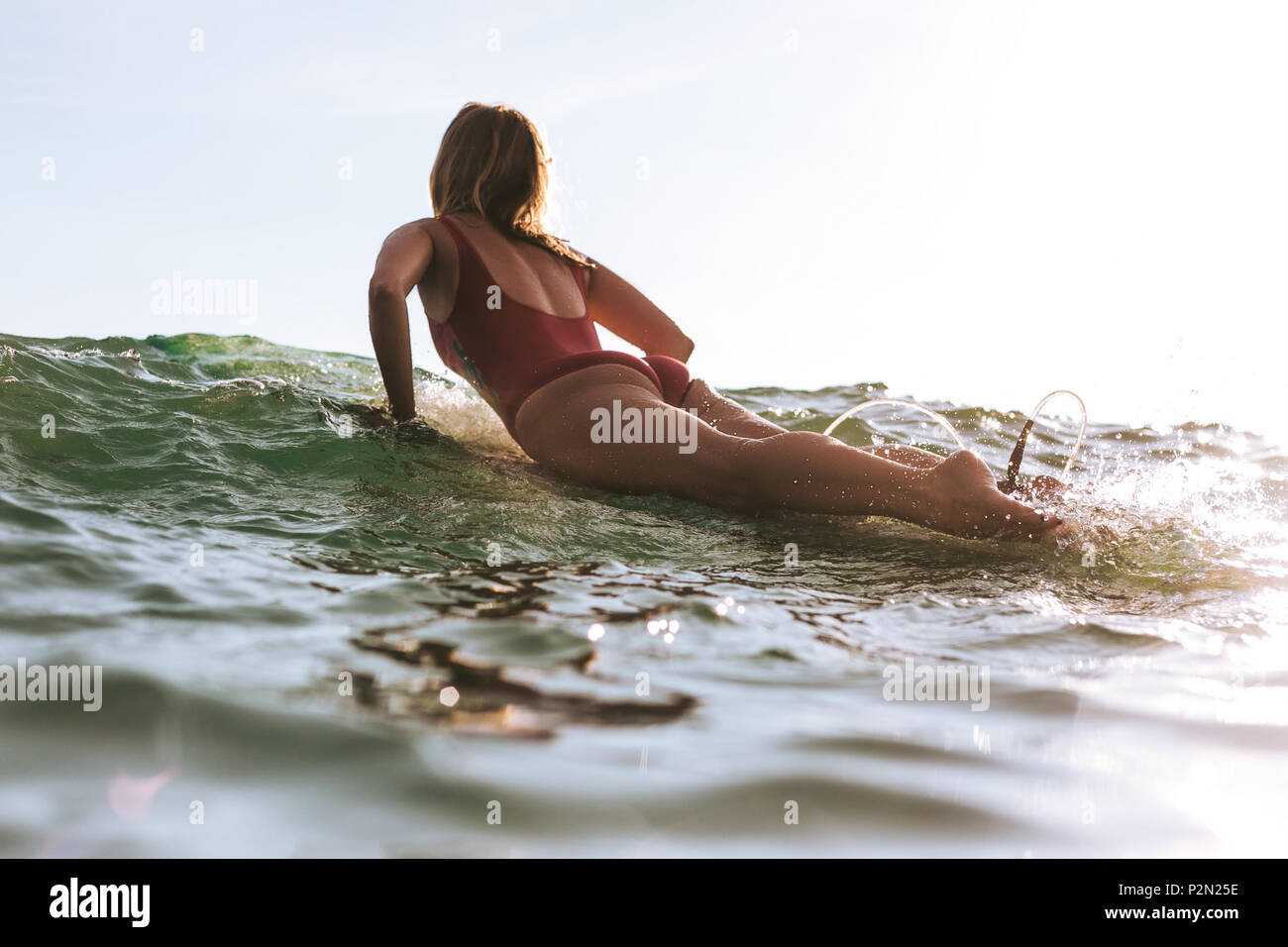 Rückansicht der Frau im Badeanzug Surfen im Ozean Stockfoto