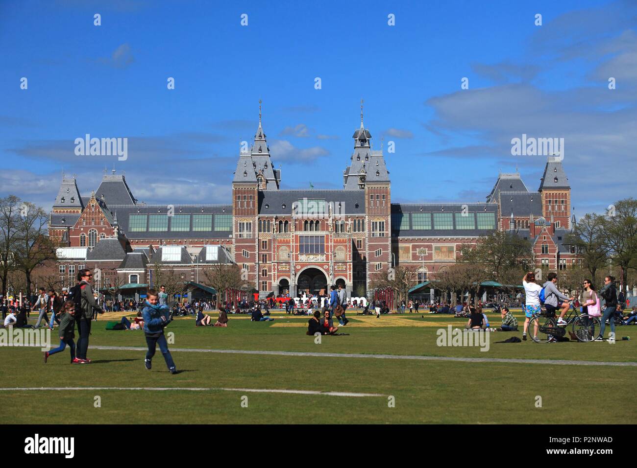 Niederlande, Provinz Nord Holland, Amsterdam, Menschen sind Erholung und Spaß auf dem Rasen der Museumplein Park, im Hintergrund das Rijksmuseum Stockfoto