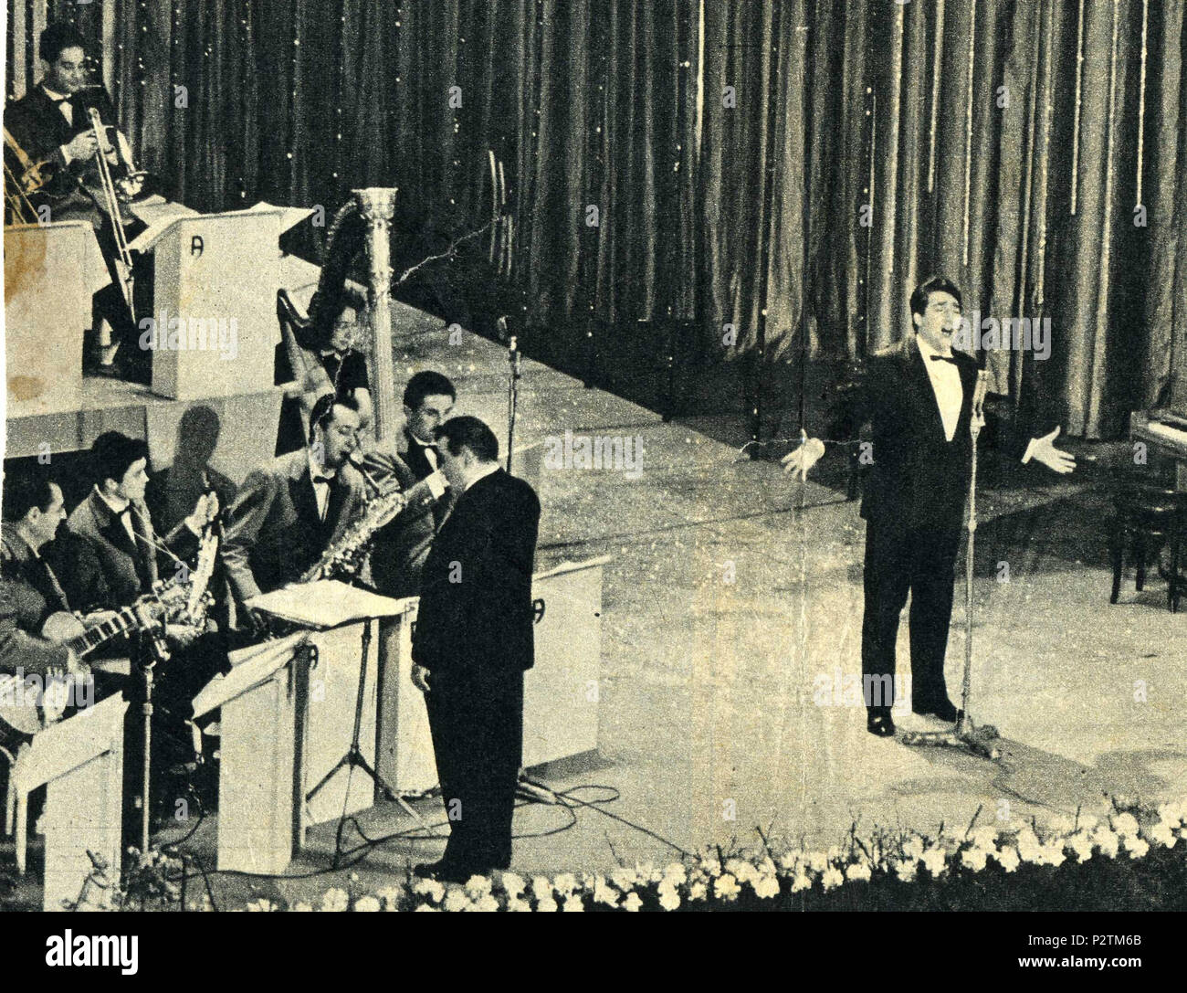 . Italiano: Festival di Sanremo 1960. Tony Dallara canta Romantica. Il chitarrista Pino Rucher (primo da sinistra) con l'orchestra Angelini. Deutsch: Das 1960 San Remo Musikfestival. Tony Dallara singt Romantica. Gitarrist Pino Rucher (1. von links) mit der angelini Orchester. Français: Tony Dallara chantant Romantica au Festival von Sanremo 1960. Le guitariste Pino Rucher (Premier à Gauche) Avec l'orchestre Angelini. 1960. Der Fotograf ist unbekannt 79 Sanremo 1960 - Tony Dallara canta Romantica Stockfoto