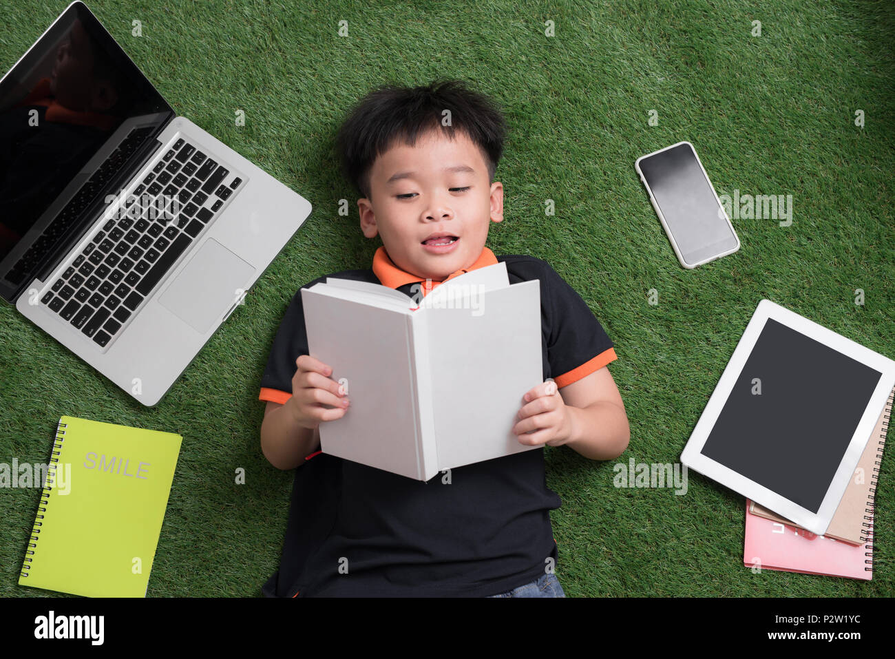 Sieben Jahre altes Kind ein Buch lesen, die auf dem Gras Stockfoto