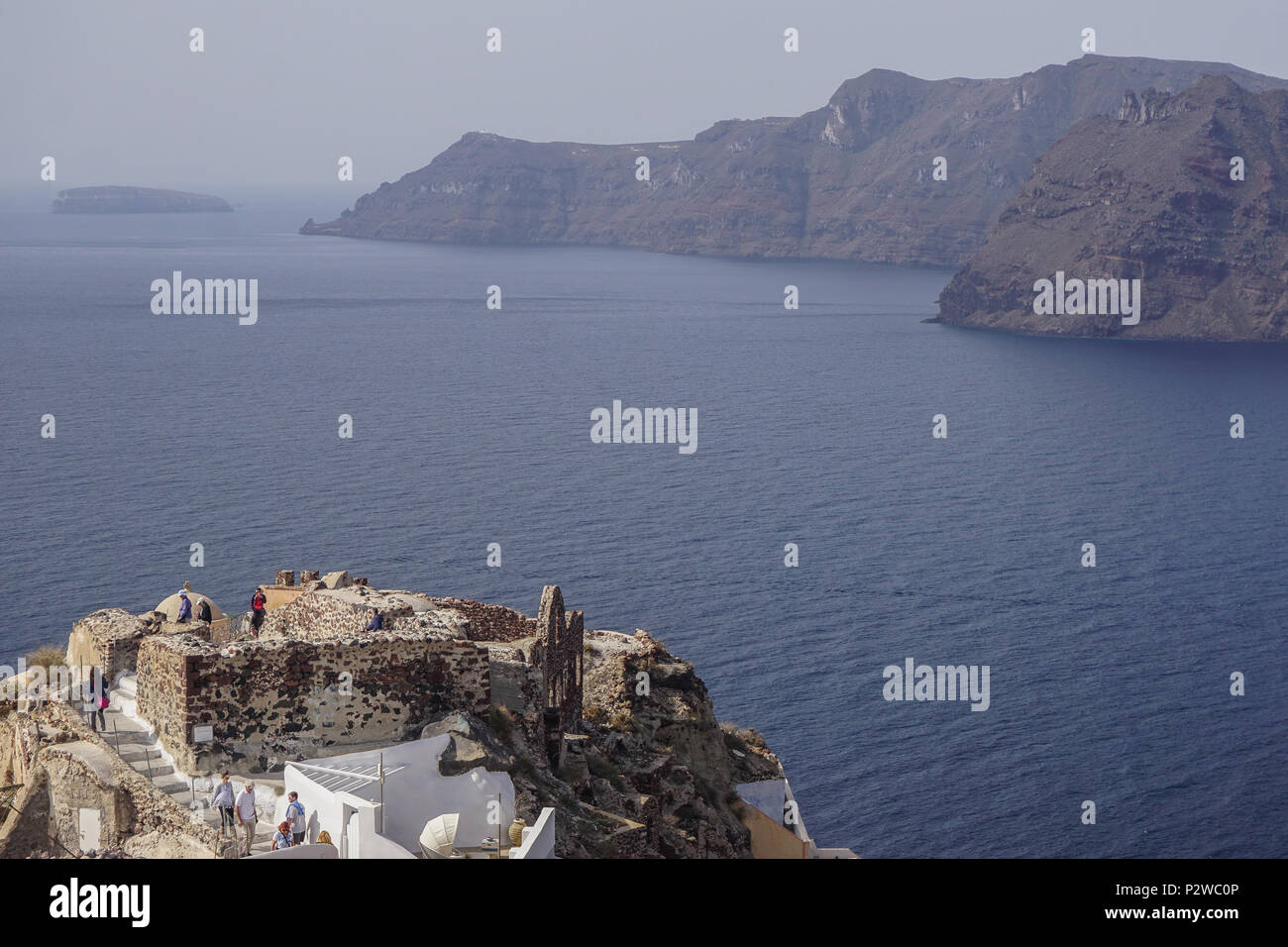 Oia, Santorini, Griechenland: Besucher auf dem Kasteli (Schloss) von Oia aus Blick über die Caldera auf der Ägäischen Insel Santorin (Thera). Stockfoto