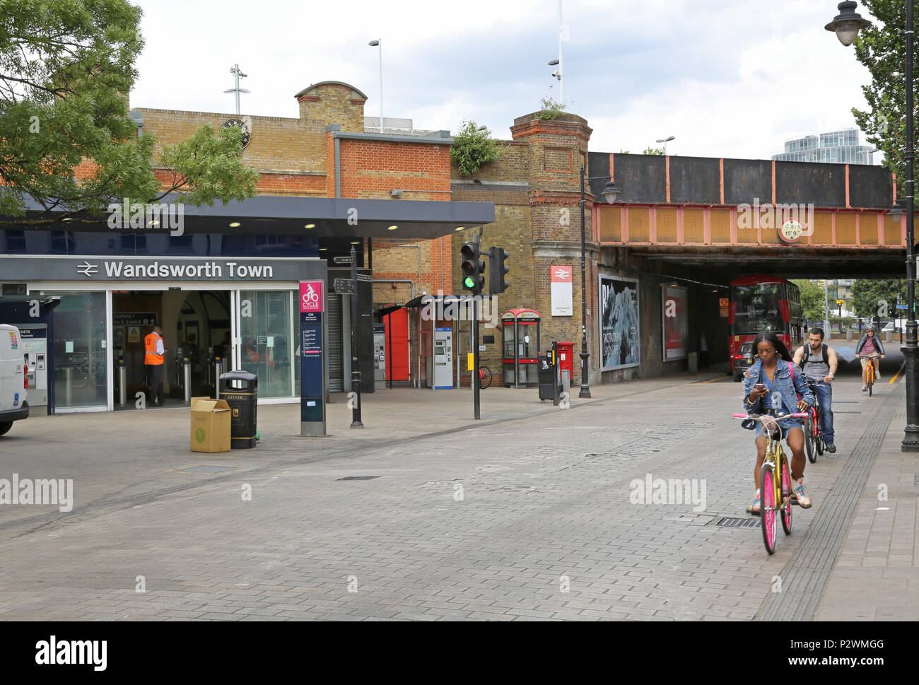 Einkaufen in der Straße vor dem Bahnhof Wandsworth Town, einem modischen Viertel im Südwesten von London, UK. Zeigt Radfahrer mit Handy während der Fahrt Stockfoto