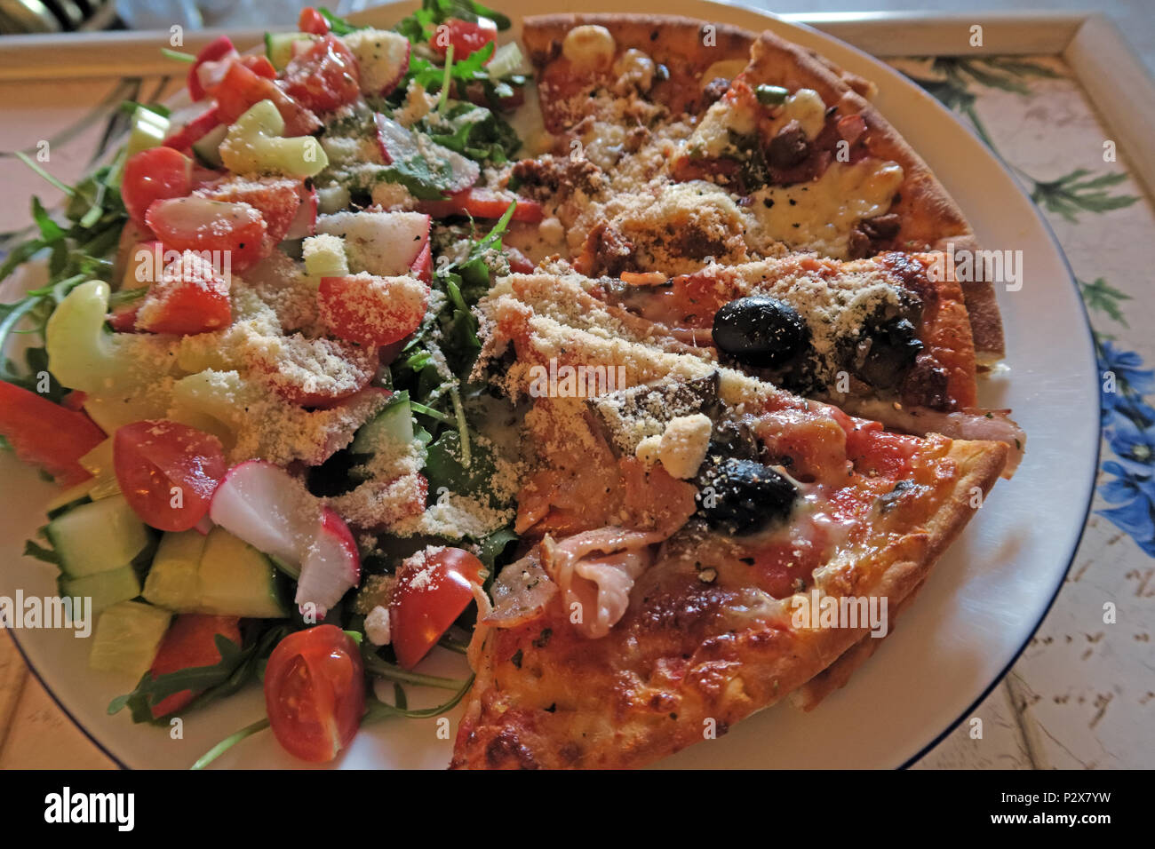 Kalorienreiche Hauspizza mit Salat, Parmesan, Oliven, Schinken, Hühnchen Stockfoto