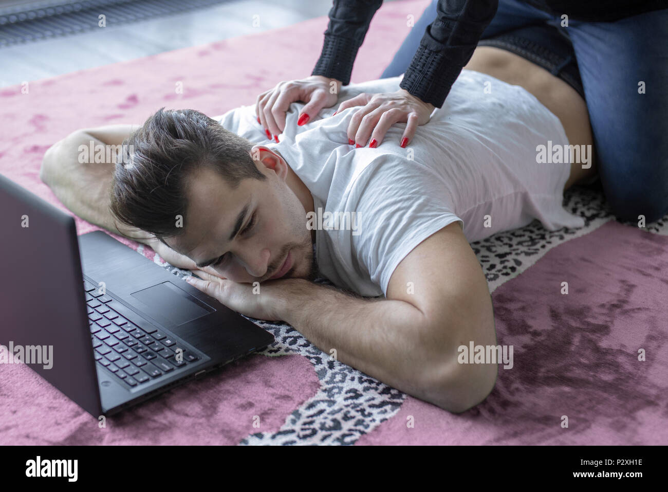 Junge müde Mann zurück Reiben von der Freundin auf dem Teppich Stockfoto