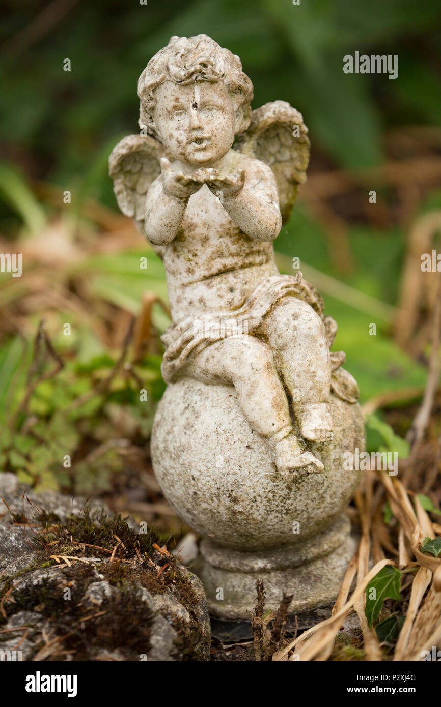 Kleine steinerne Figur eines geflügelten Cherub, Eros oder Amor weht ein Kuss in der Nähe von Garten Teich. Lancashire North West England UK GB Stockfoto