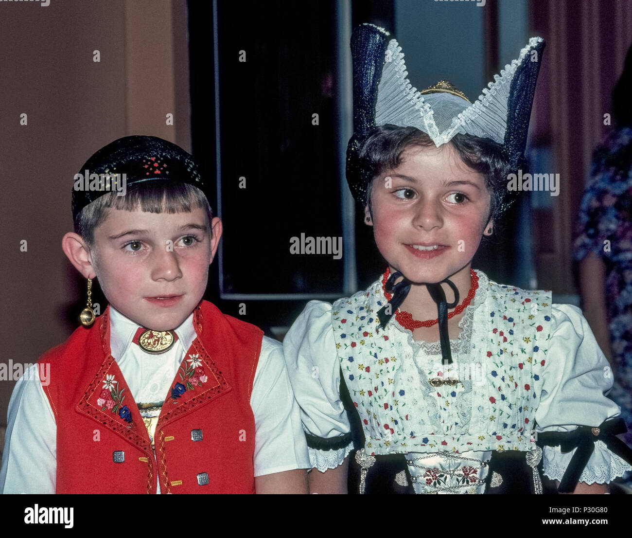 Ein junger Schweizer Junge und Mädchen stellen in ihren traditionellen  Trachten für Flash Foto auf einem Festival in Appenzell, Schweiz.  Bekanntmachung Golden Earring des Jungen, ähnelt einem kleinen creme  Schöpfkelle, seine rote