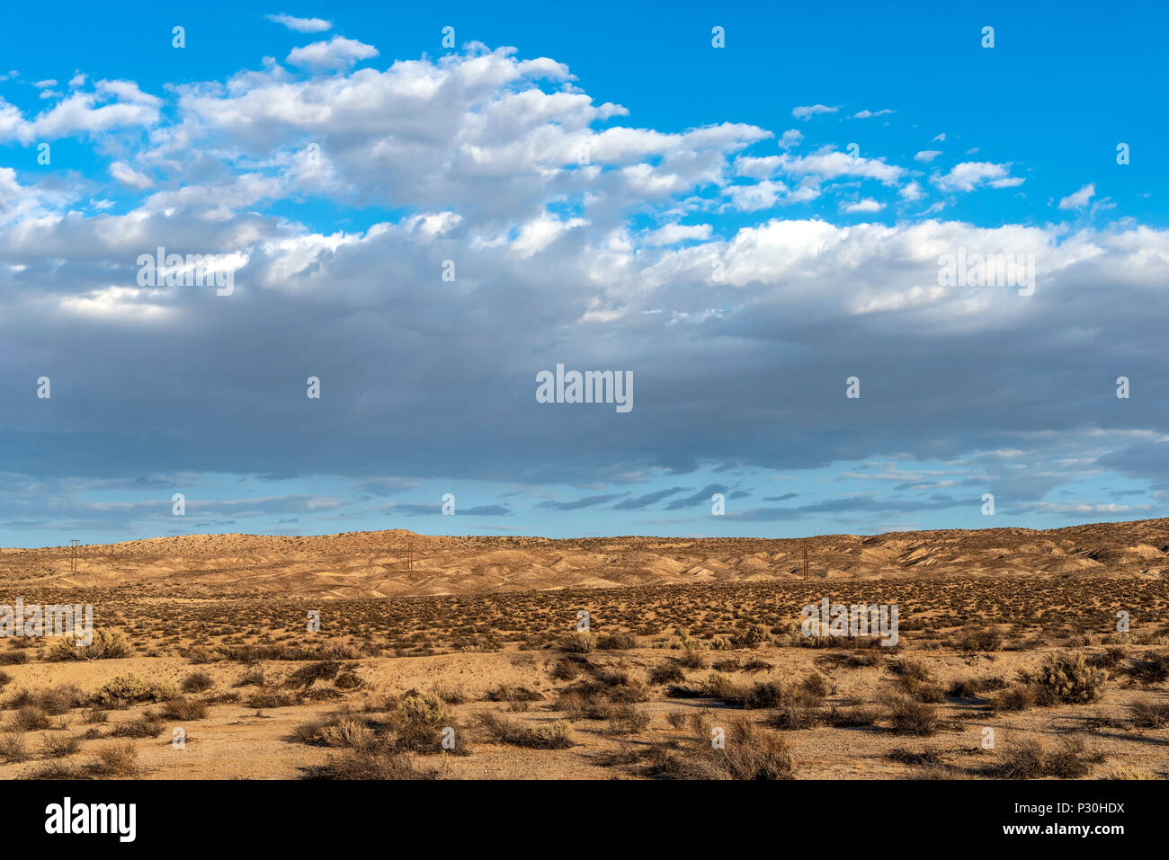 Heiße, trockene Wüste unter einem blauen Himmel mit Wolken. Stockfoto