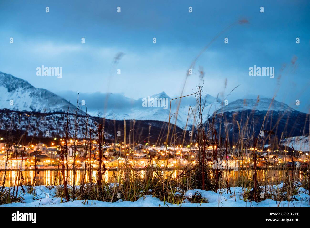 Die Lichter der Stadt Ushuaia sind im Wasser der Bucht nieder. Der Winter ist gekommen und der Schnee die Berge und das Tal. Stockfoto