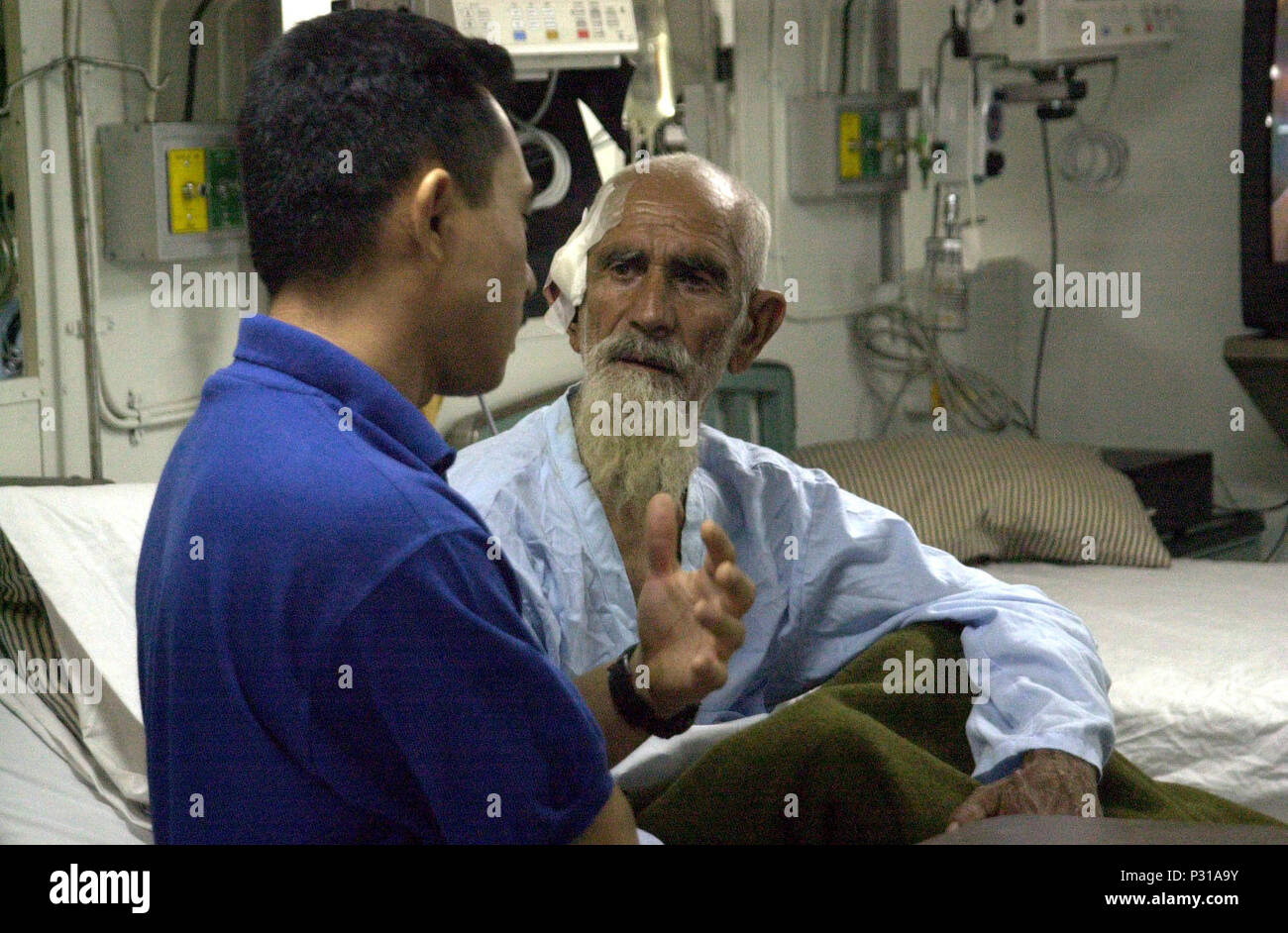 Meer an Bord der USS Peleliu (LHA 5) Dez. 9, 2001 -- ein Seemann, der an Bord der USS Peleliu (LHA 5) wirkt als Dolmetscher für seine shipÕs Besatzung und ihre Gäste - Mitglieder von Hamid Kharzai im Südlichen Allianz Gruppe. Mehrere der afghanischen Kämpfer wurden vor kurzem an Bord der amphibische Kriegsführung Schiff übernommen und in die onboard Krankenhaus Einrichtungen behandelt für Verletzungen bei einem Bombenanschlag empfangen. Stockfoto