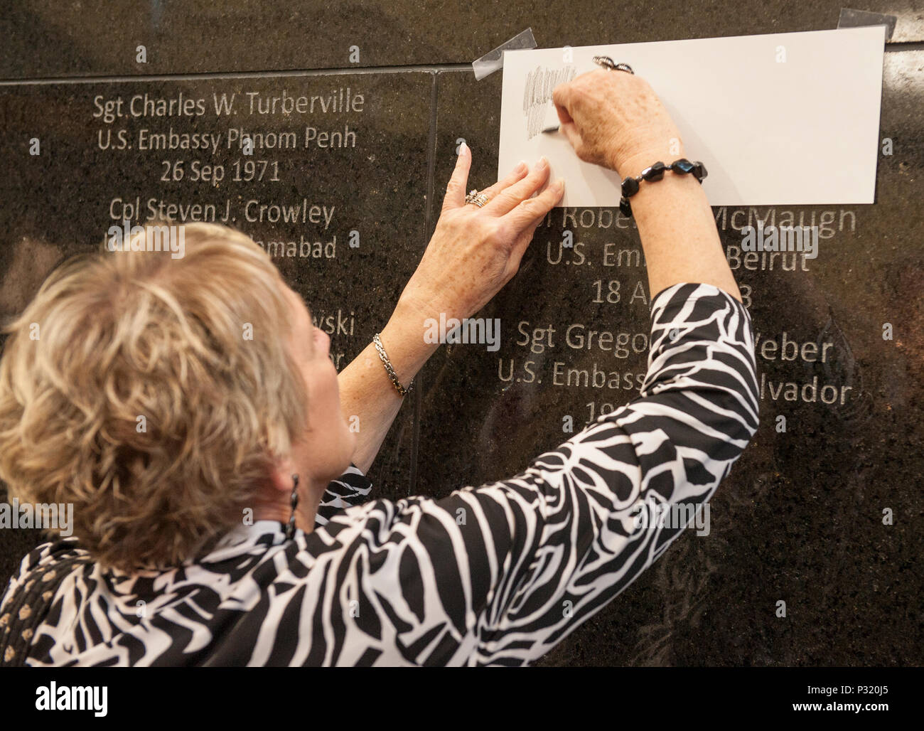 Eine Frau reibt die Widmung an der Wand einen gefallenen Geliebten Namen zu kopieren, US Marine Corps Lance Cpl. Darwin L. Richter, der bei der US-Botschaft in Saigon stand, während eine Wand Einweihung nach der Marine Corps Embassy Security Group (MCESG) Ribbon Cutting für die Eröffnung des neuen MCESG Hauptquartier (HQ) an der MCESG Compound, Quantico, Virginia, 12.08.2016. Die spezielle Wand Widmung wurde zu Ehren der Gefallenen MCESG Marines, die dazu beigetragen, die Welt Mission - bereit, um die Nationen Botschaften vom Terrorismus und feindliche Geheimdienste zu schützen. (U.S. Marine Corps Foto von Staf Stockfoto