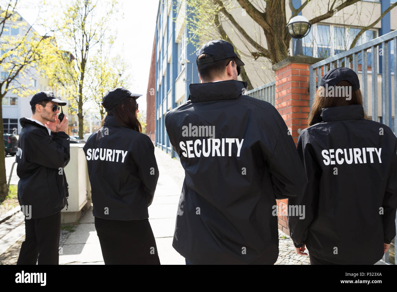 Ansicht der Rückseite des Sicherheitsleute in schwarzen Uniform stehen außerhalb des Gebäudes Stockfoto