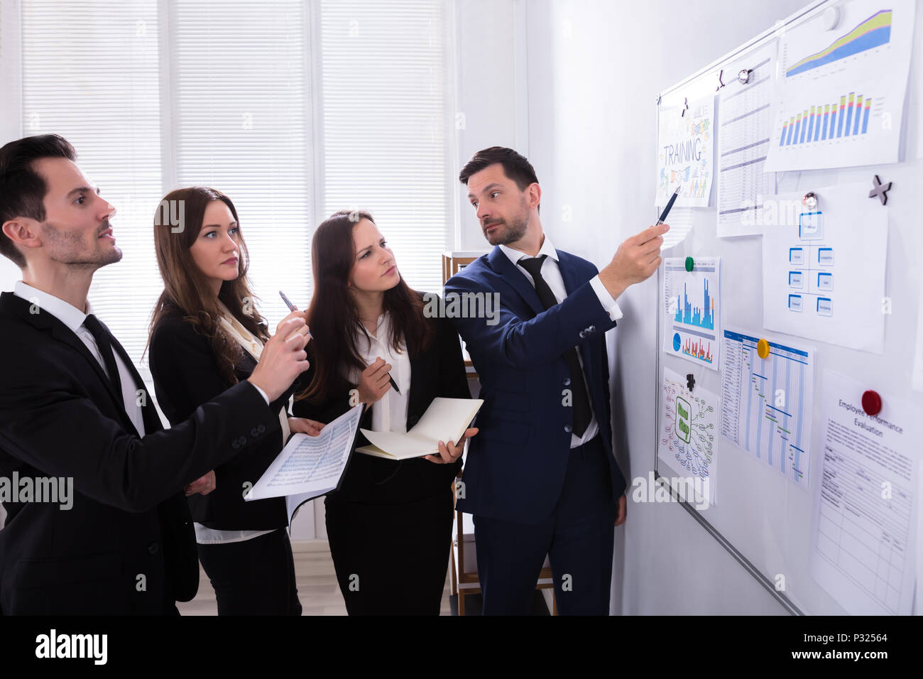 Gruppe Junger Geschäftsleute Analyse Diagramme auf der Tafel am Arbeitsplatz Stockfoto