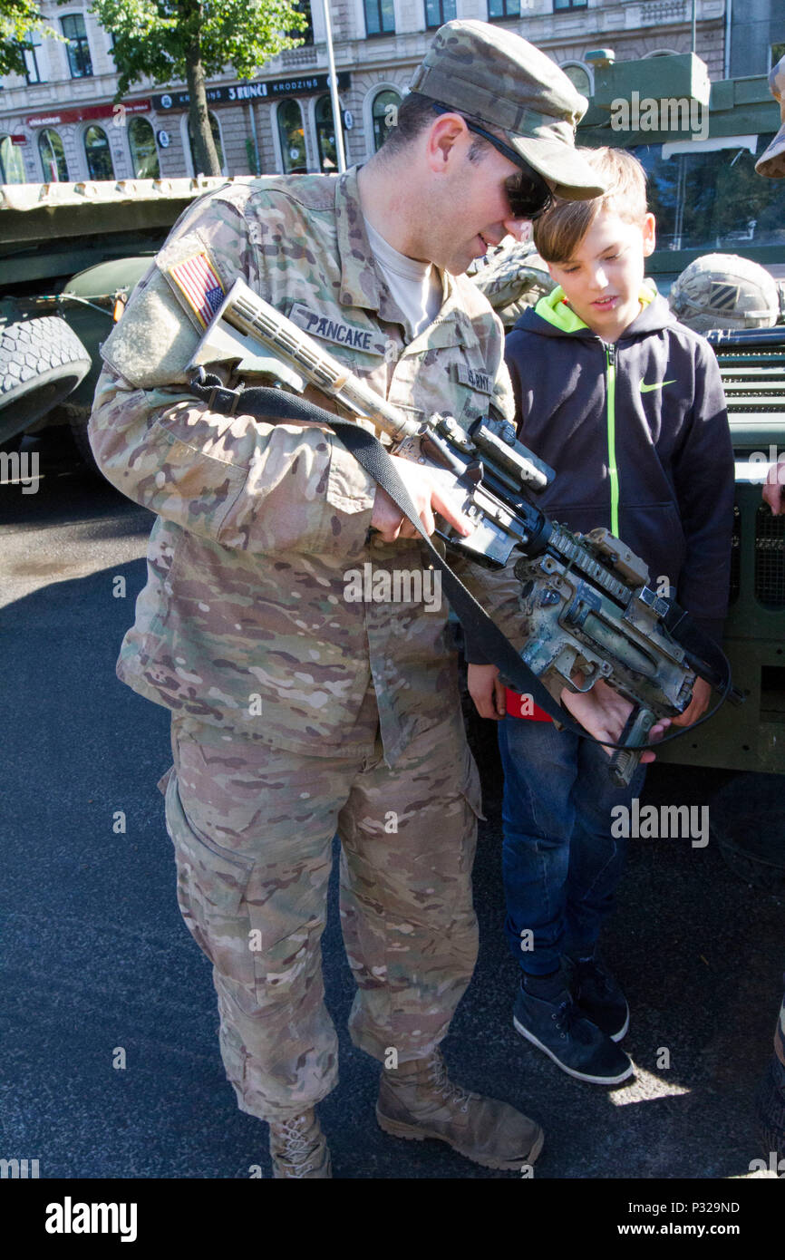 Us-Armee Pfc. Draven Pfannkuchen, ein Eingeborener von Petersburg, Ind. und ein infanterist zum 3. Kombinierte Waffen Bataillon zugeordnet, 69. Armor Regiment, 1. gepanzerte Brigade Combat Team, 3rd Infantry Division, erklärt der US-Army Ausrüstung Bürger an einem statischen Anzeige für das 25-jährige Jubiläum des Lettischen nationalen Schutz in Riga, Lettland, 20. August 2016 auf Lettisch. Die Soldaten aus dem 3 Mrd., 69. Arm. Rgmt., an dem Ereignis beteiligt, ein Training mit ihren Ostsee Verbündeten zur Unterstützung der Operation Atlantic lösen, einem US-amerikanischen LED-aufwand in Osteuropa durchgeführt werden, zeigen US-Engagement für die Stockfoto