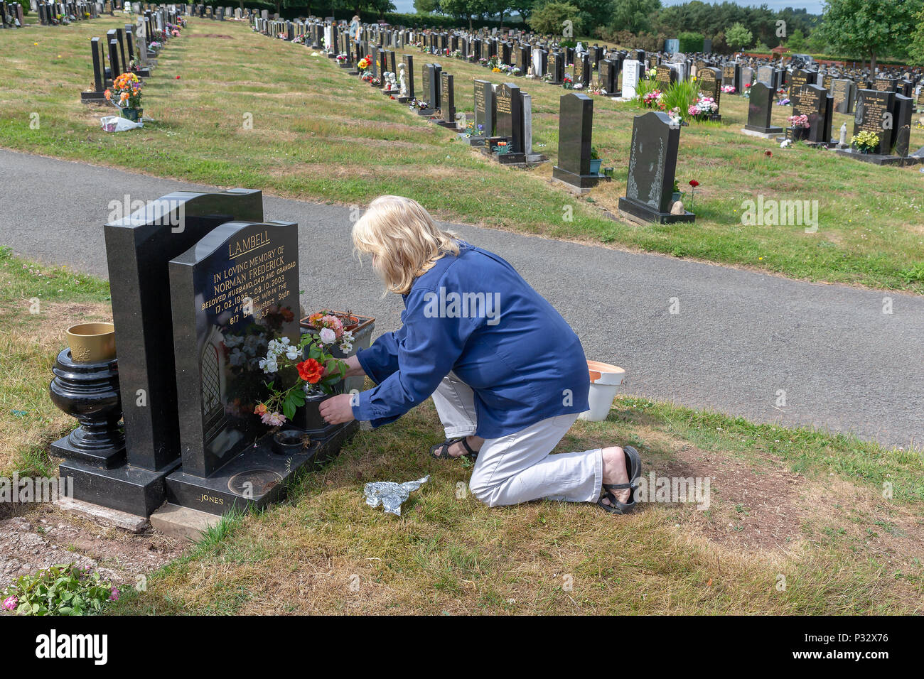 Warrington, Großbritannien, 17. Juni 2018 - Vatertag - Reife blonde Lady verbindet viele andere, indem sie Blumen auf dem Grab ihres verstorbenen Vaters. Fox Verdeckte, Warrington, Cheshire, England, UK Credit: John Hopkins/Alamy leben Nachrichten Stockfoto