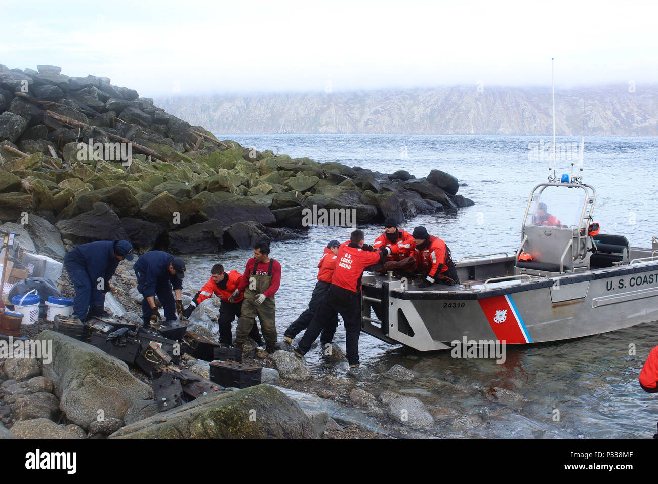 Besatzungsmitglieder von der Coast Guard Cutter SPAR arbeiten neben Einheimischen von der Insel Little Diomede elektronische Abfälle auf kleinen Boot SPAR laden ordnungsgemäß entsorgt werden, auf dem Festland August 25, 2016. SPAR, in Kodiak, Alaska homeported, besuchte die Insel als Teil der Arktis Shield 2016. U.S. Coast Guard Foto von Petty Officer 1st Class Austen Shannon. Stockfoto