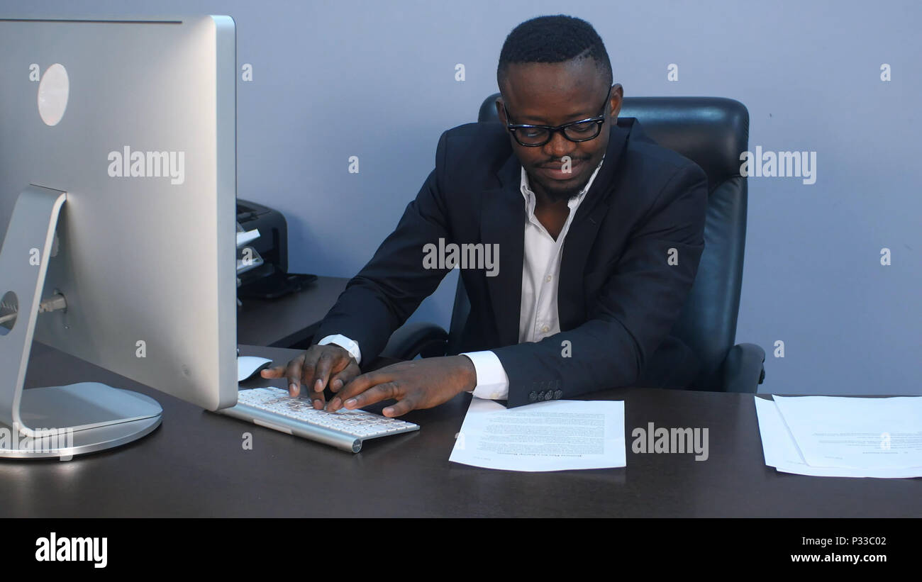 Porträt der jungen Ernst afro-amerikanischen Geschäftsmann arbeiten mit Laptop und Dokument Stockfoto